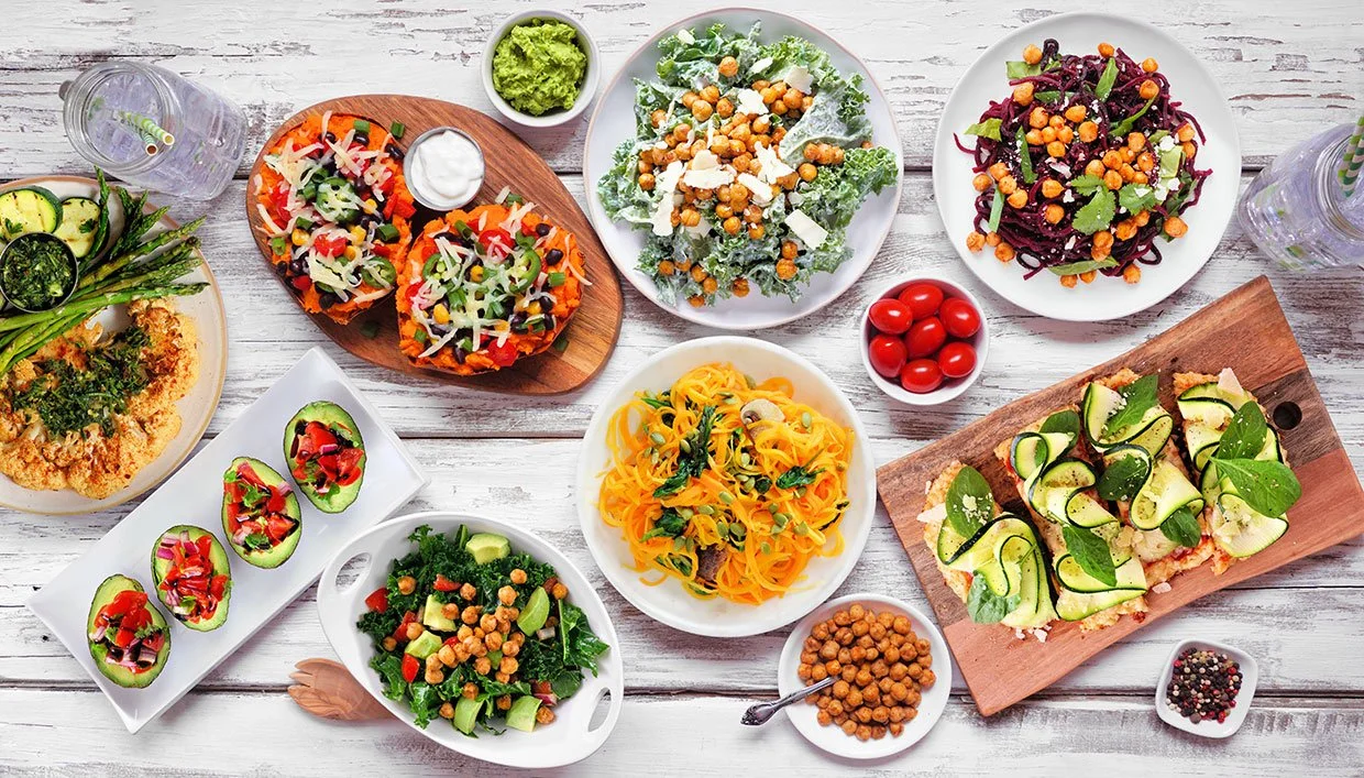 Assorted salads and veggies on a white wooden table