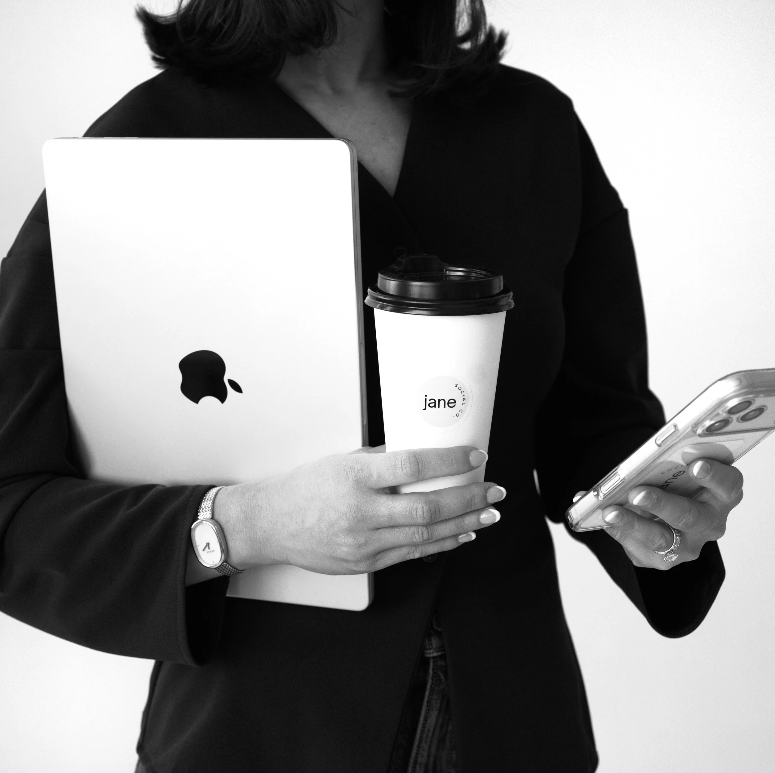 A woman holding a laptop, a coffee cup labeled 'jane', and a smartphone.