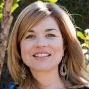 A woman with shoulder-length blonde hair smiling outdoors with greenery in the background.