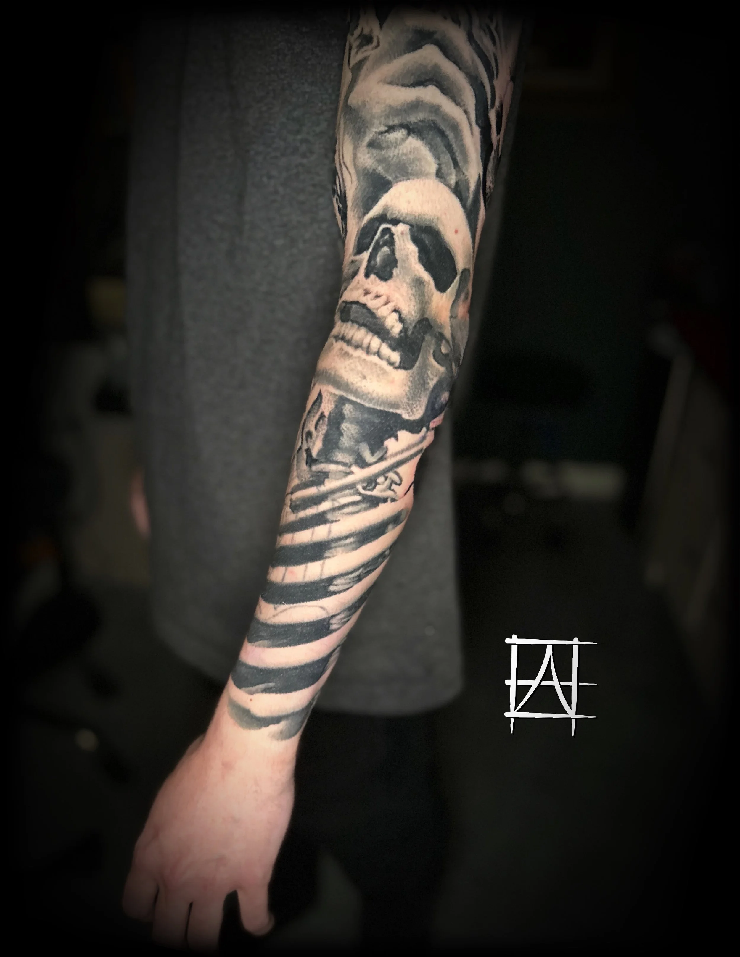 Tattooed arm with a skull and ribcage  on it.