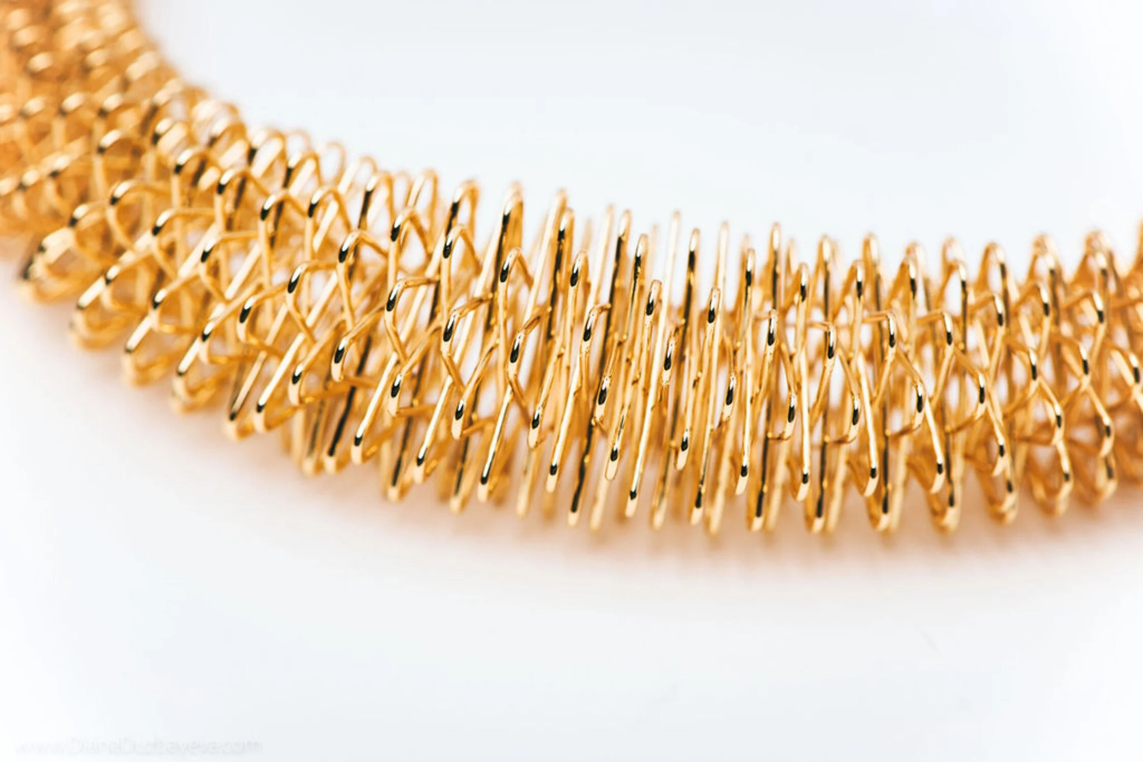 Close-up of a gold metallic hair accessory with twisted and interwoven loops, resembling a hair comb or ornament.