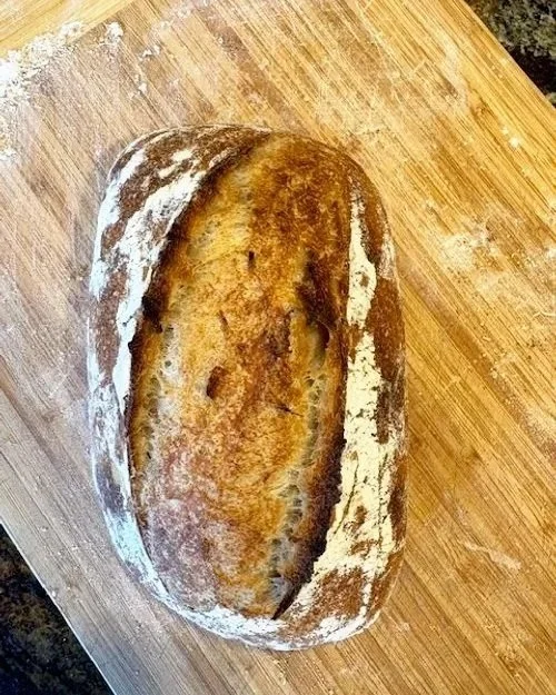 A loaf of bread with a face-like appearance, resting on a wooden cutting board.