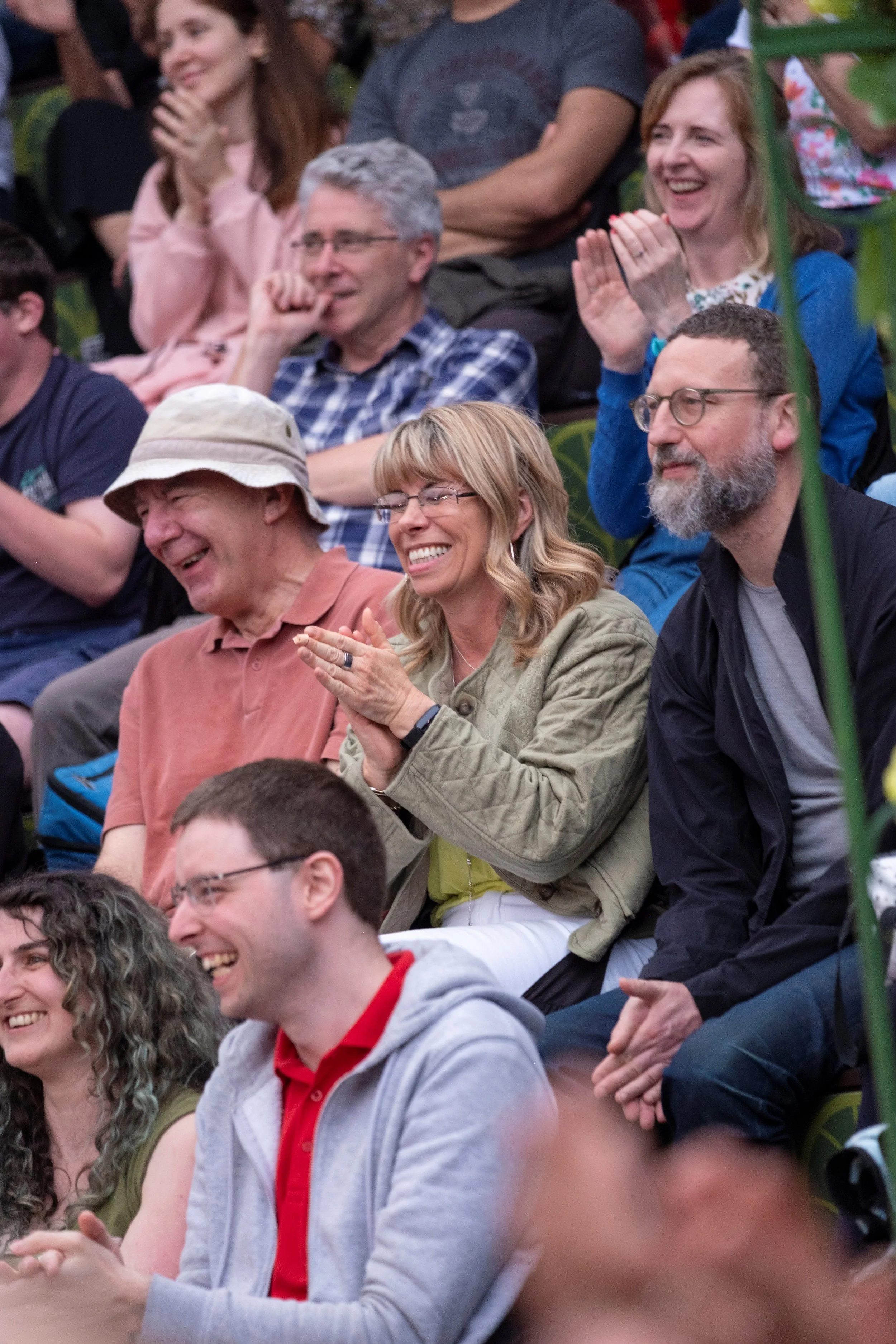 Group of people laughing and clapping at an outdoor event.