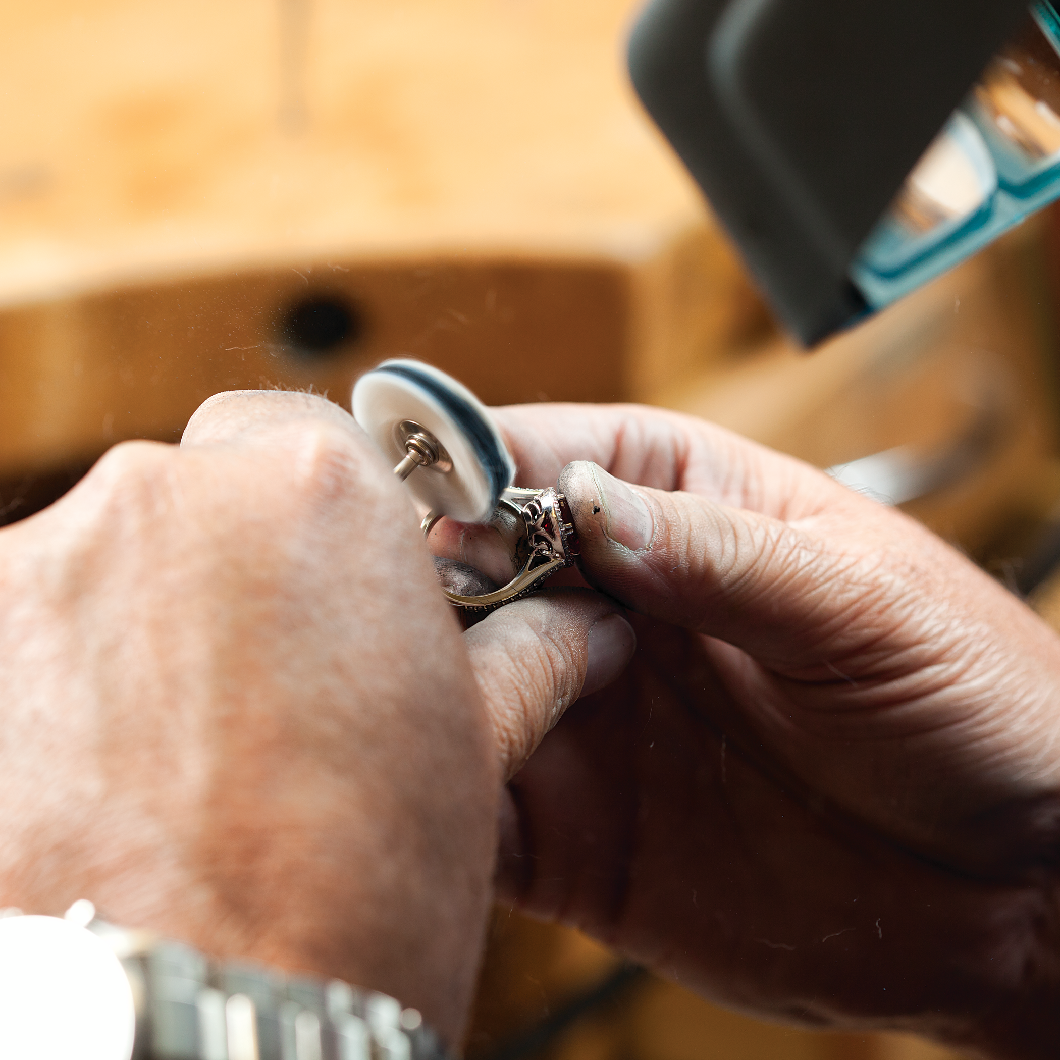 A Jeweler hand polishing a white gold anniversary band.