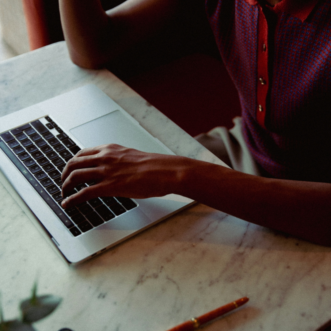 Hands typing on a laptop at a desk, representing SEO content writing and strategic digital planning