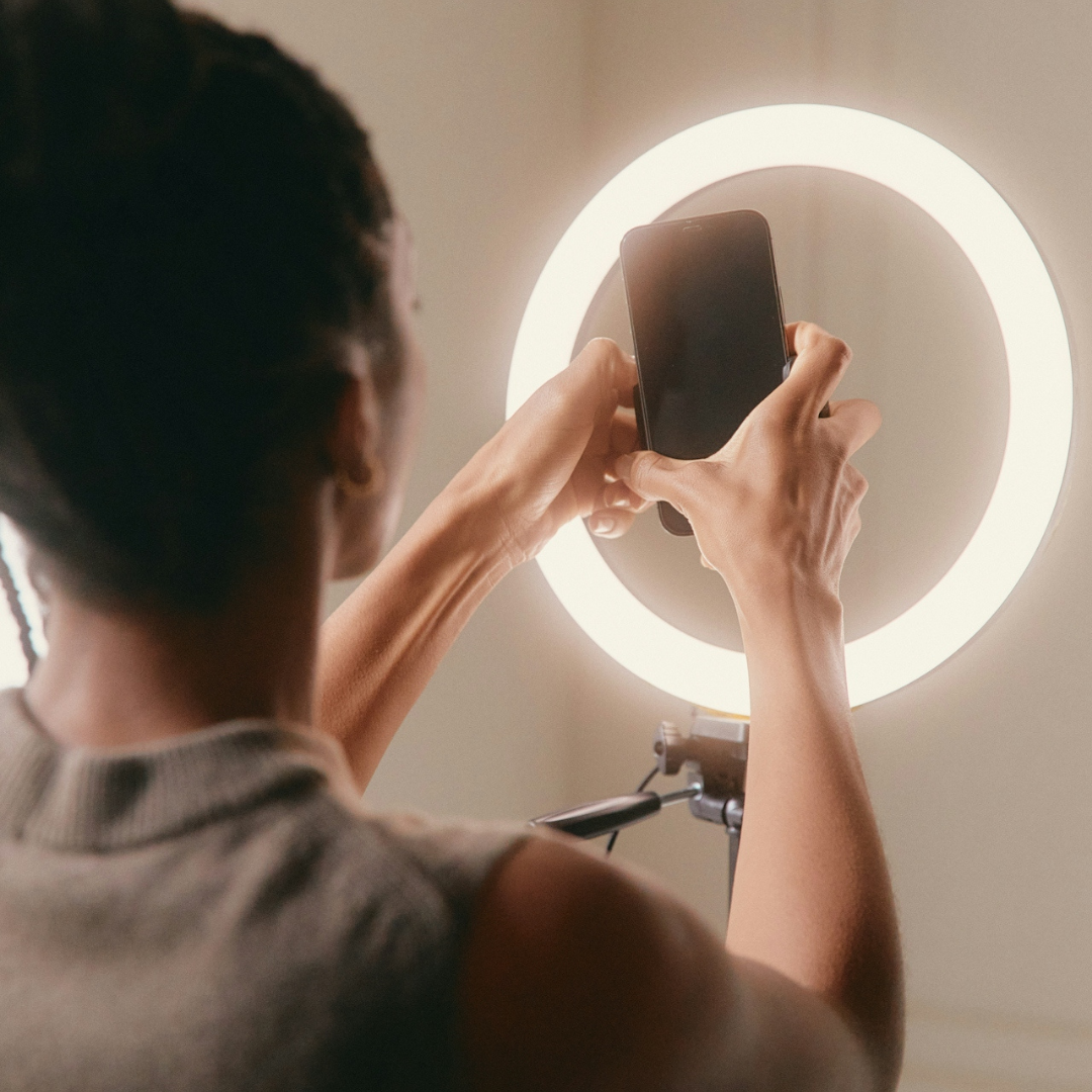Creator filming content with a smartphone and ring light for brand visibility and digital marketing