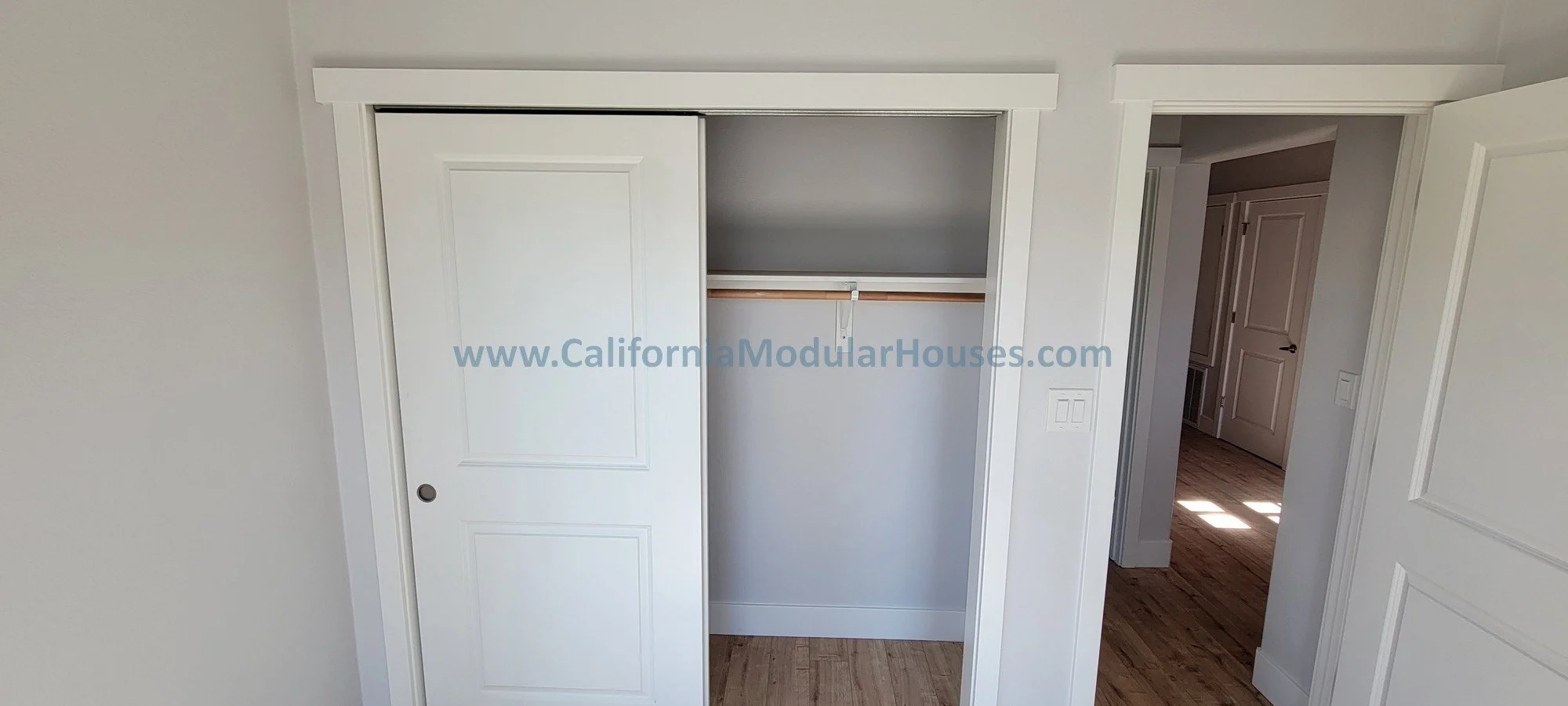 Empty built-in closet with sliding door and wooden floor in a room.