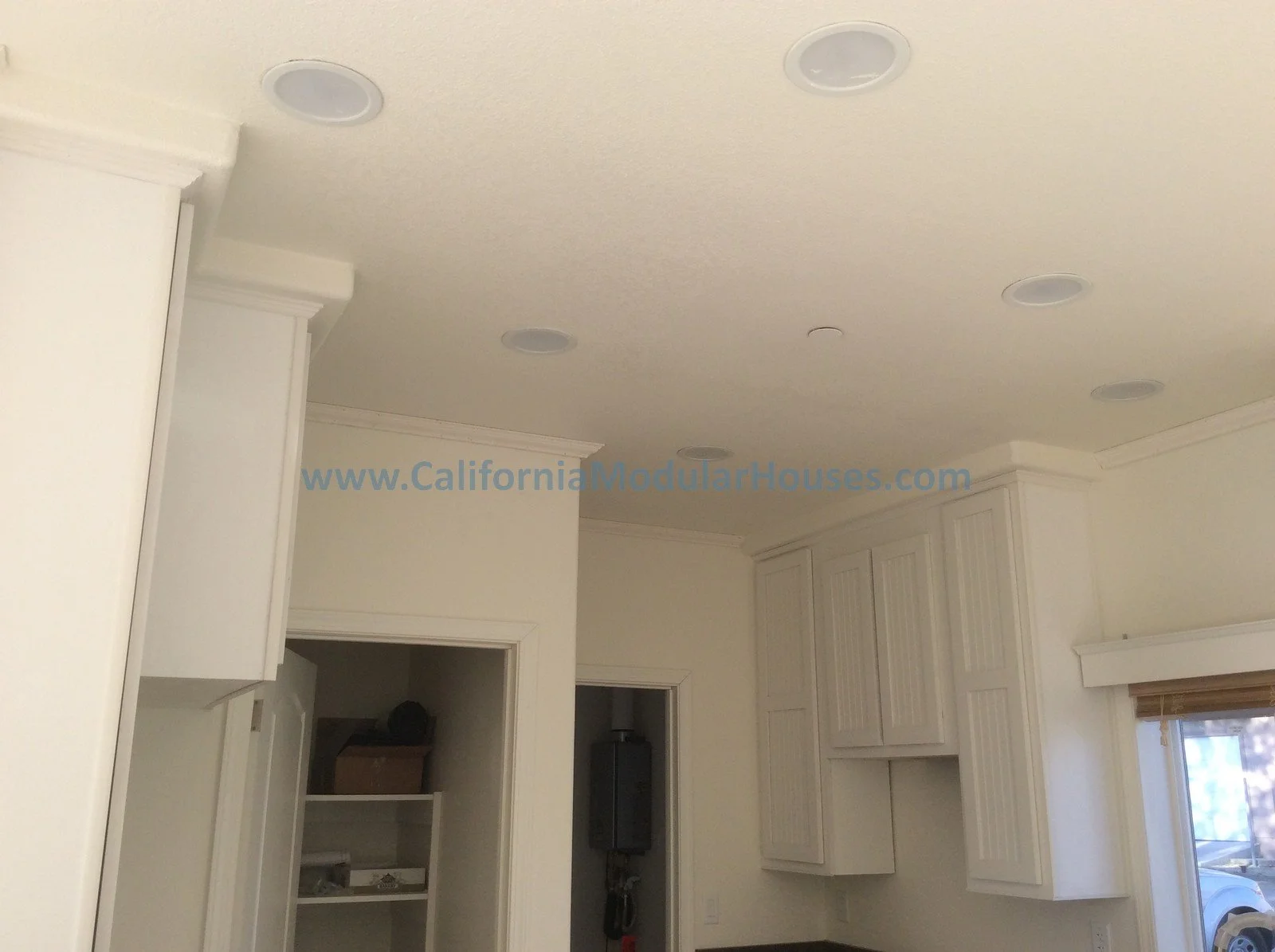 Interior of a room with white cabinets, crown molding, and this website URL written on the ceiling: www.CaliforniaModularHouses.com