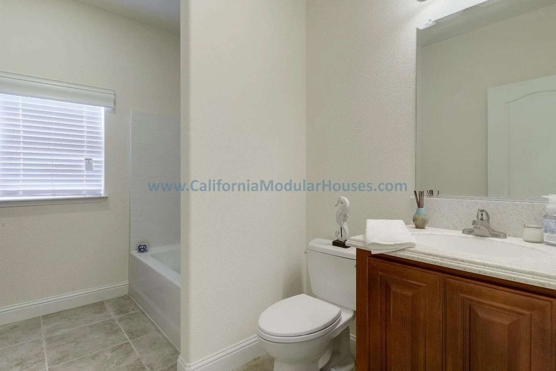 Bathroom with window, bathtub, toilet, and wooden vanity with mirror. Bay Area Prefab Modular Home, Modular Home CA, California Modular Homes,