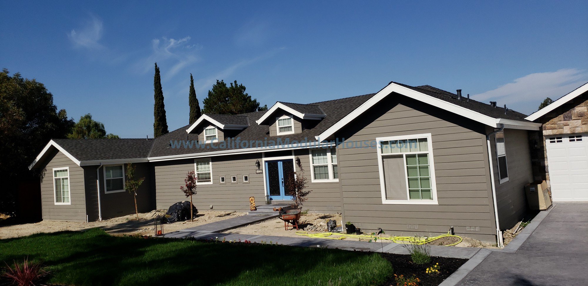A newly  constructed modular home with gray lap siding, white trim, and a blue front door. City of Concord, Contra Costa County, California.  Modular Home.   