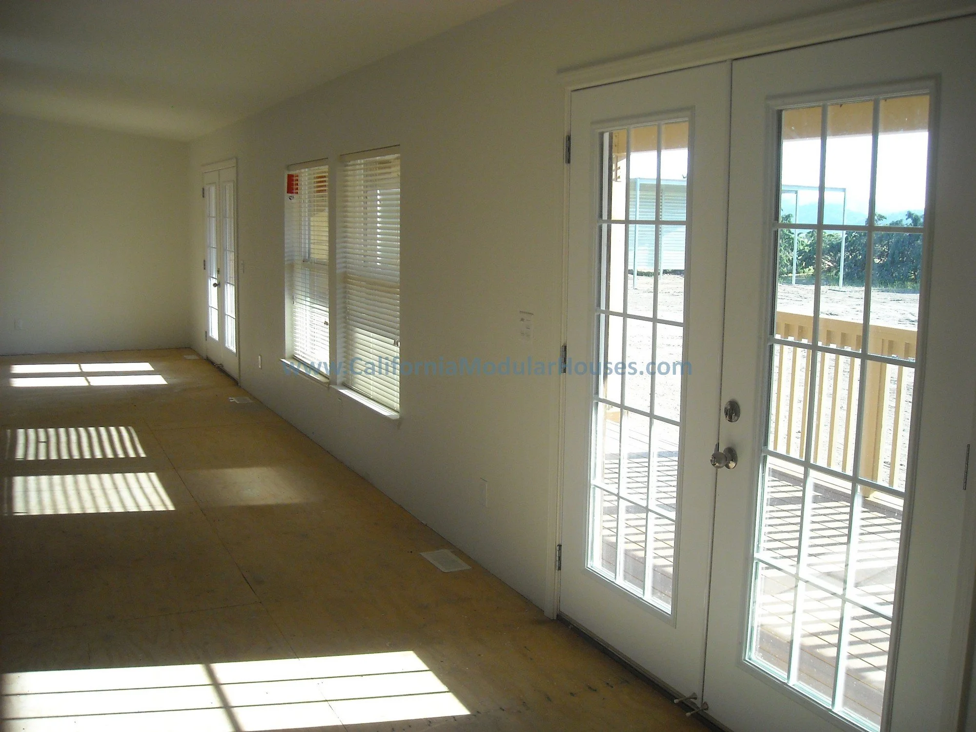White walls, windows, and glass doors leading outside, with tons of sunlight streaming in in this very large "Great Room".  This is part of our custom designed Hollywood Series of homes, the Hollywood Maxim.  