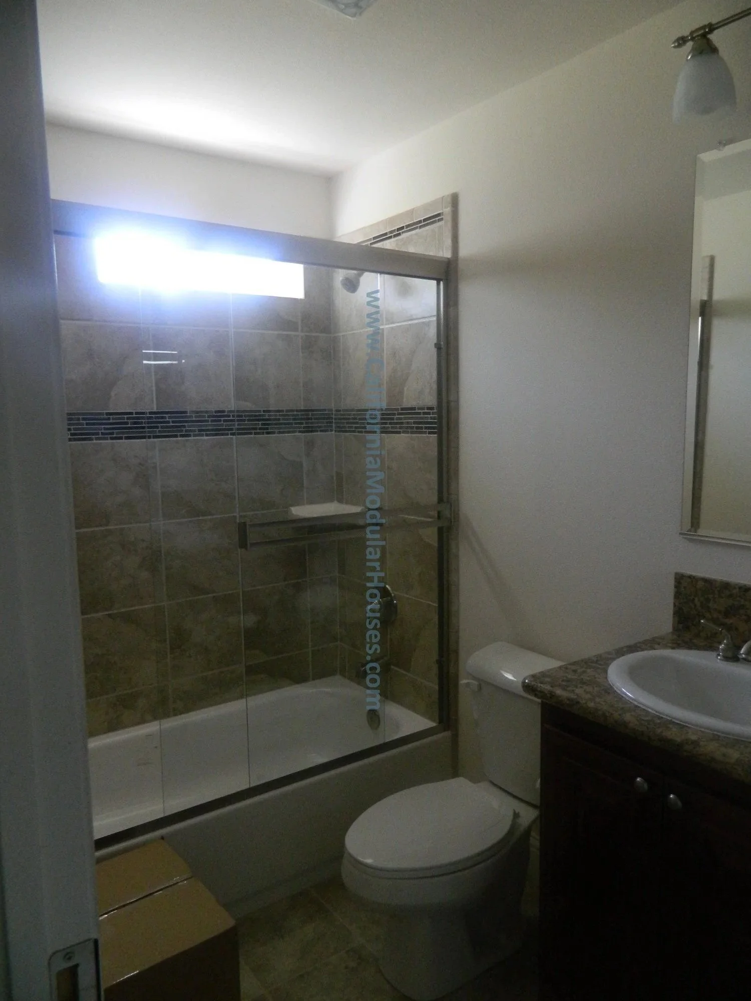 Bathroom with a glass shower enclosure, toilet, and a vanity with a granite countertop and sink