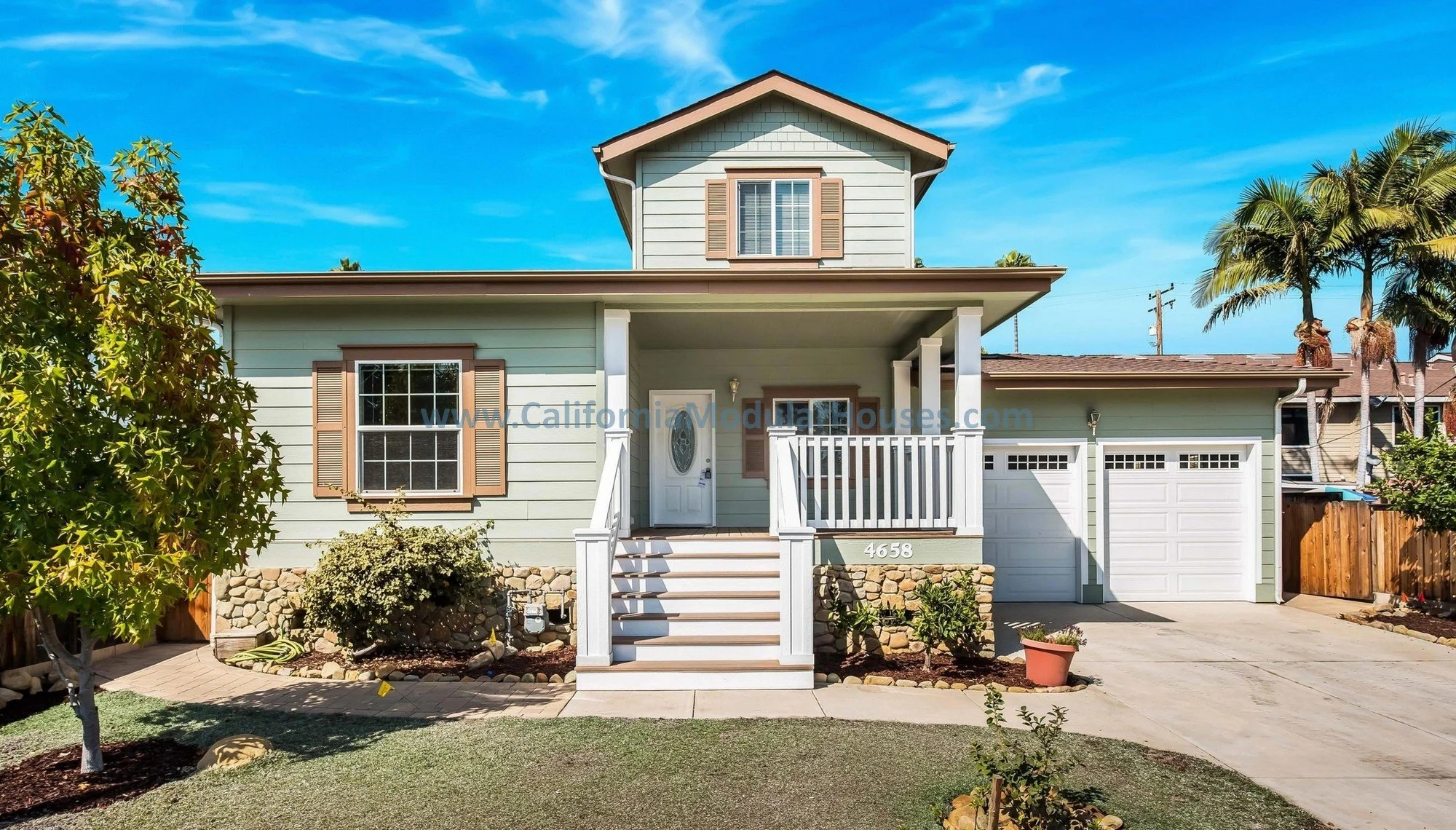 Sage green, brown trim prefab modular, two-story home. White door, white railing.