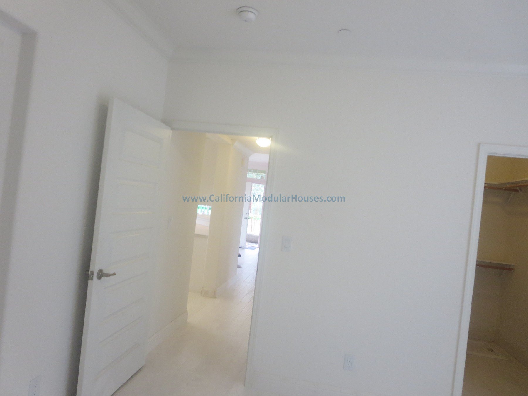 Modulars.   Napa, CA.  Prefab.  California Modular House. California modular home.  Modulars.   Empty room with white walls, an open door leading to another room, and a closet with wooden shelves, in a house under construction.