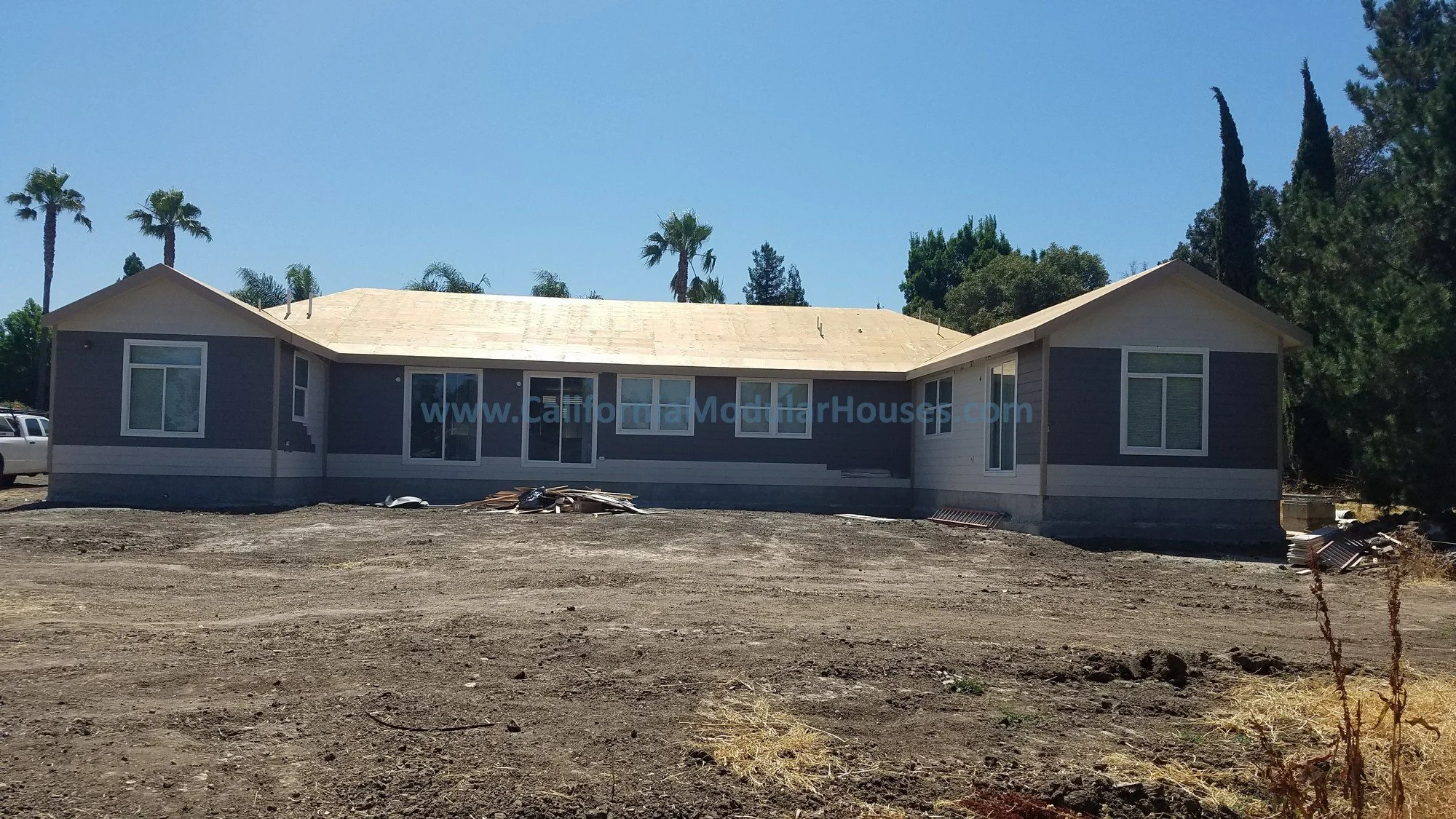 This shows the siding that was completed in the factory in gray, then the roof was completed on-site since the roof pitch prevented it from being delivered with the roof completed.  This view is from the rear.  Pre-Fab Home.    