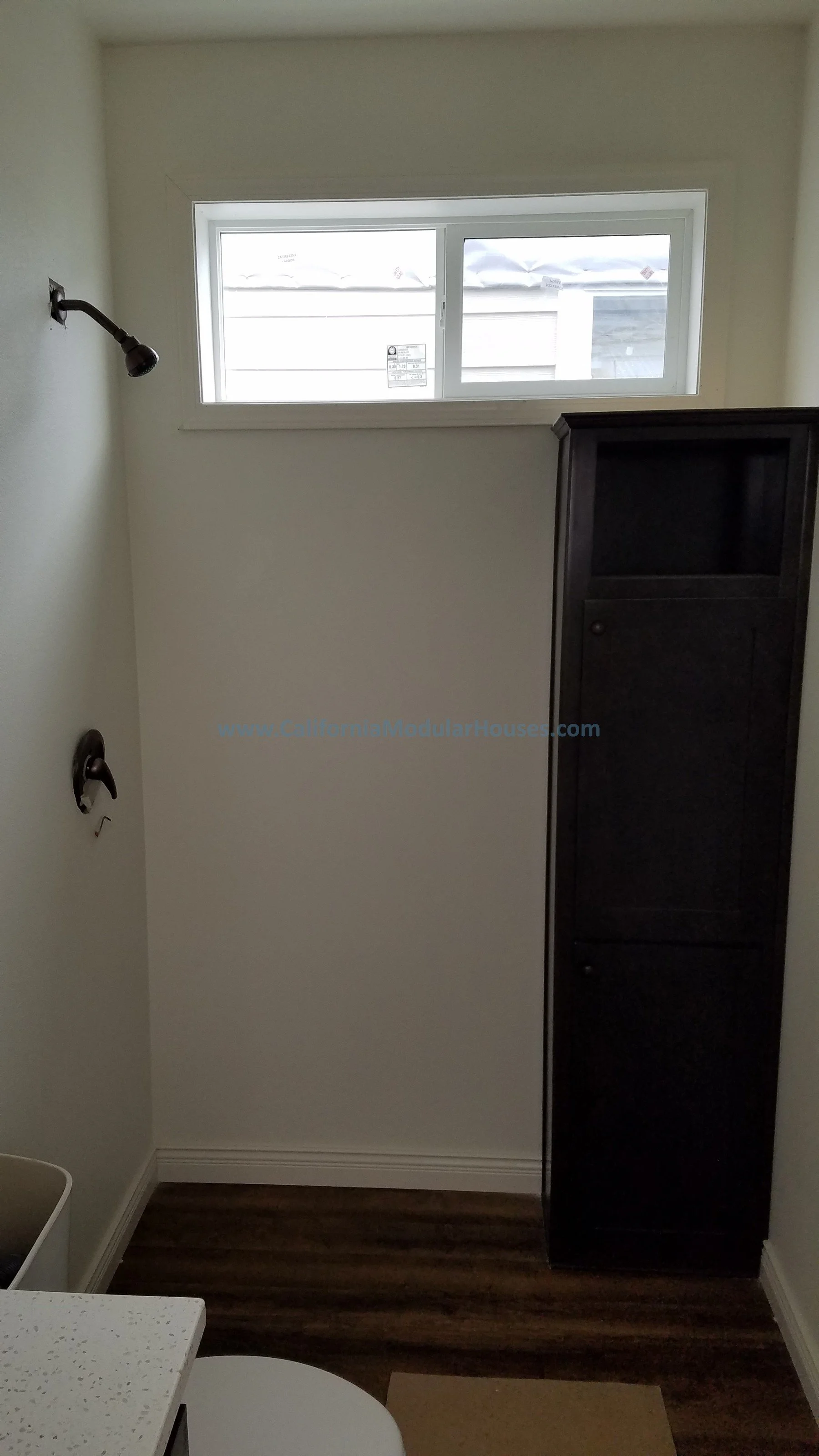 Empty bathroom with a window, a dark cabinet, and a towel bar.  Modular Homes, California Modular Home,  California Modular,