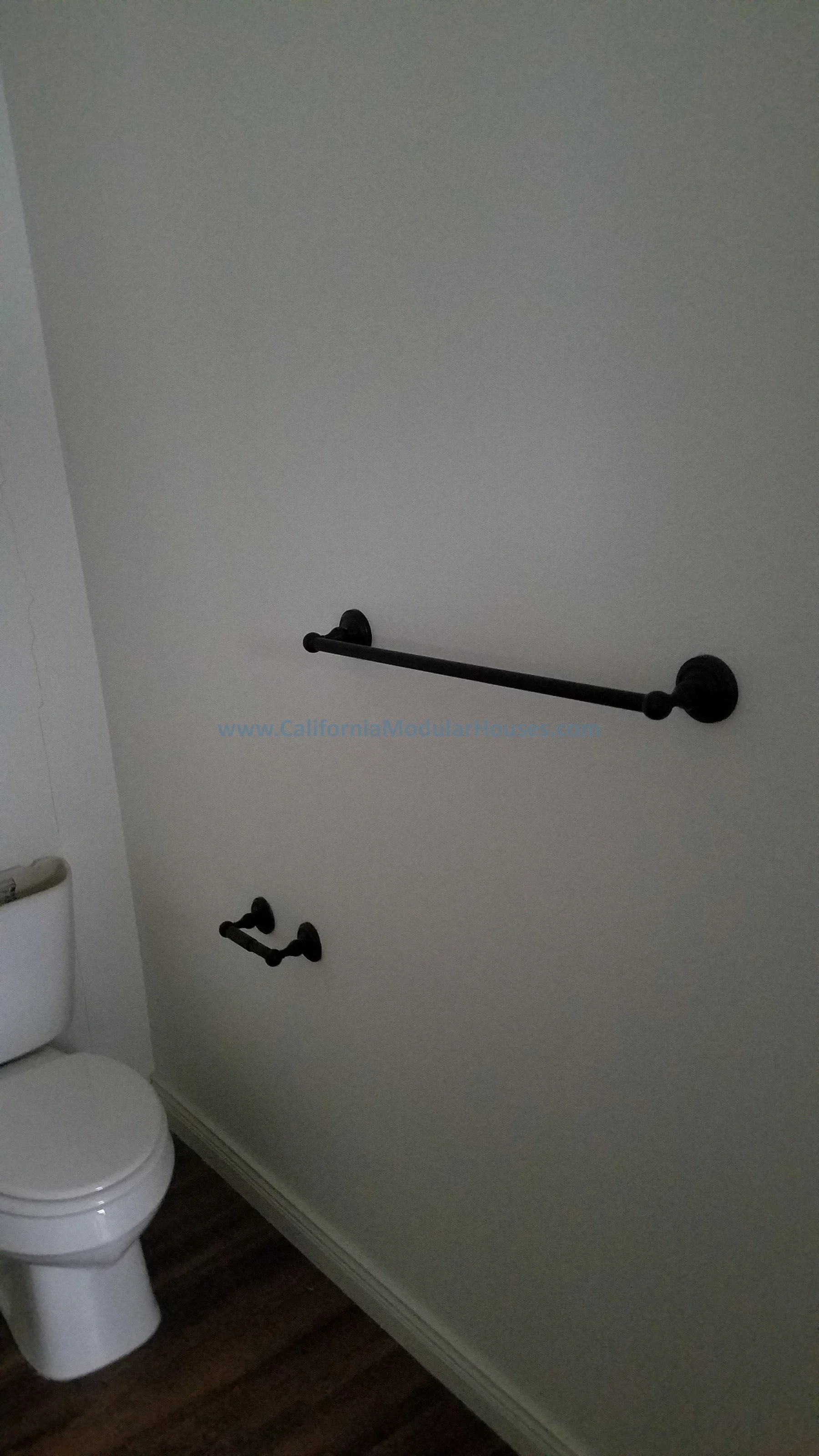 Bathroom with toilet and two black grab bars on the wall, one longer and one shorter.  Modular Home CA, California Modular Homes, Prefab Modular Homes California,