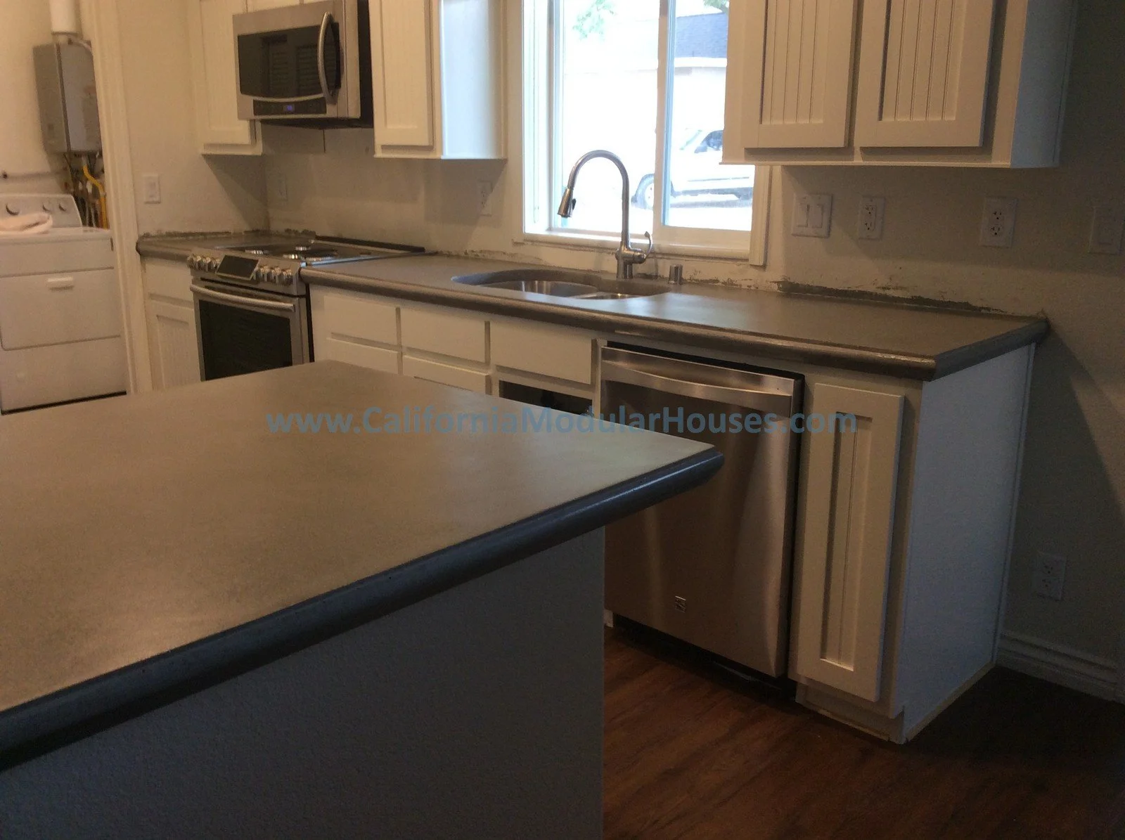 Kitchen with white cabinets, stainless steel appliances, a window above the sink, and a wooden countertop island.