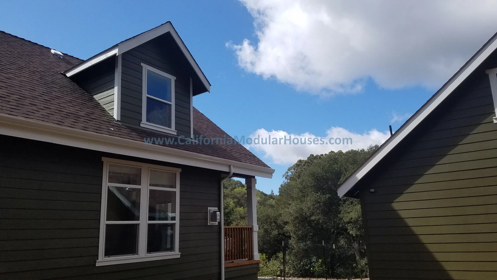 This view shows beautiful windows with transom windows over them to allow for maximum lighting, nicely centered with the dormer above and the site built garage to the right.  Pre-Fab.  