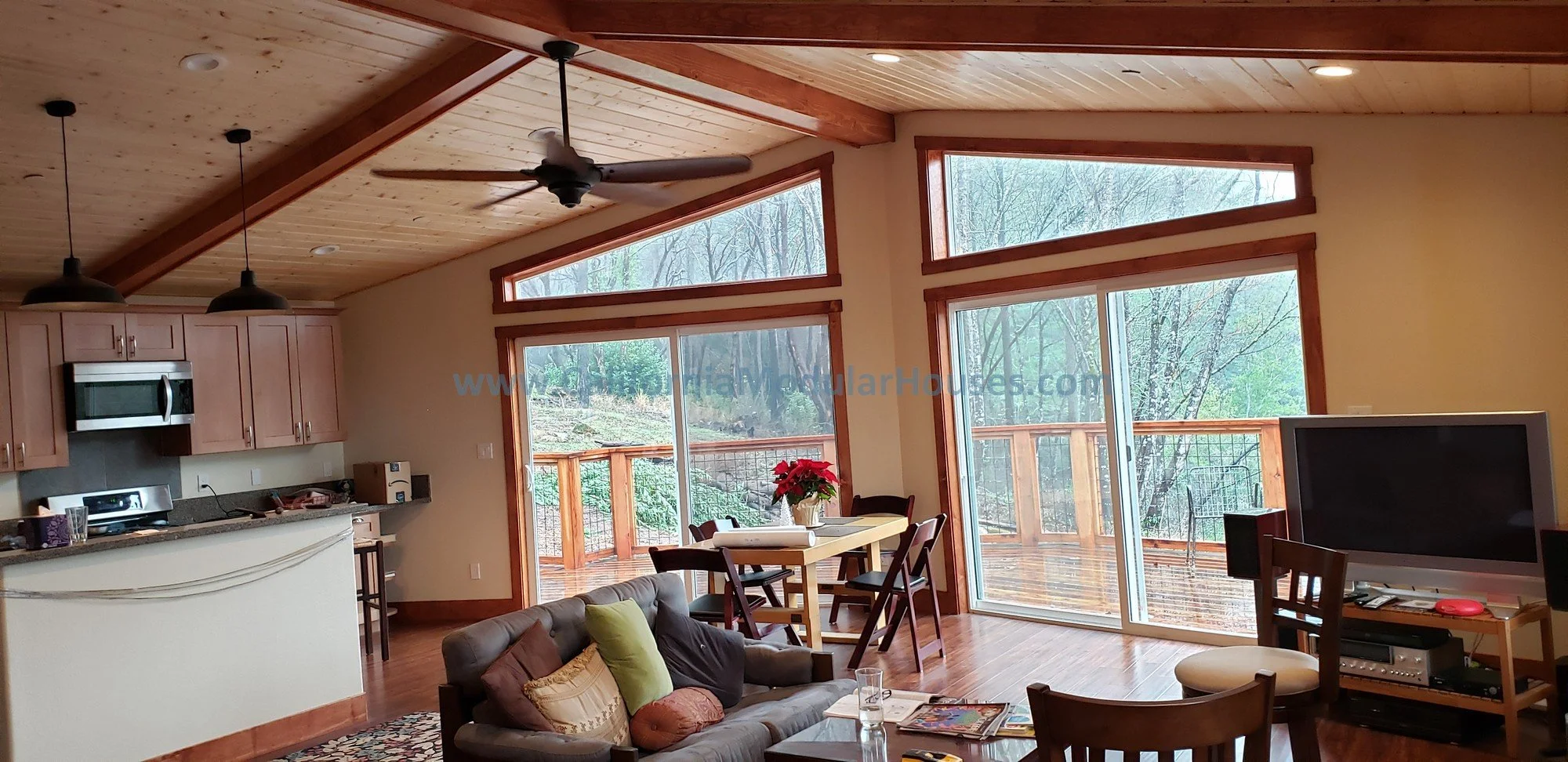 Look at this view with the sliding glass doors and transom windows in this modular home!  The interior ceiling cedar siding was done after the home was delivered with decorative beams and a perfectly placed ceiling fan.  Pre-Fab.