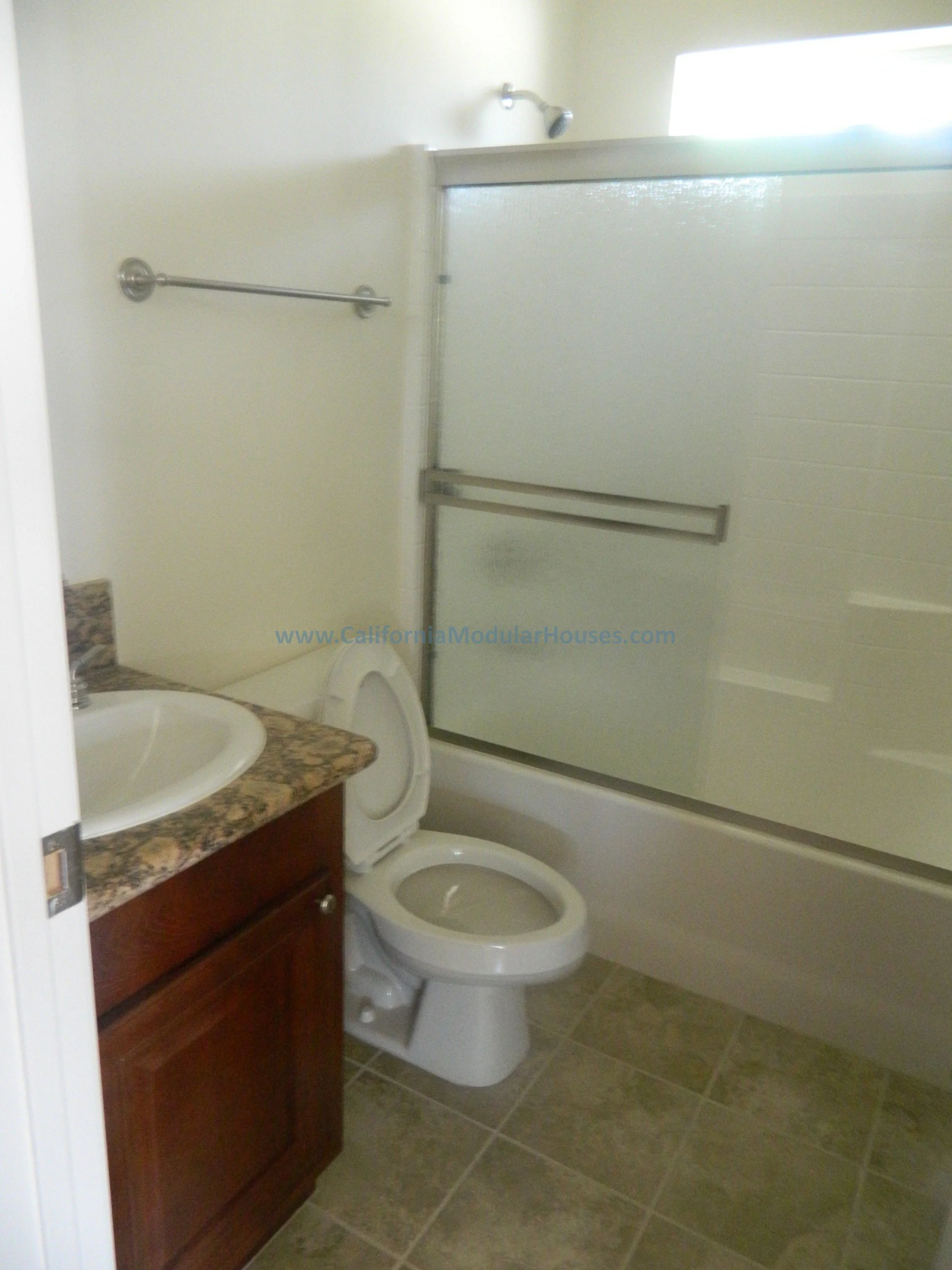 Bathroom with a shower stall, toilet, and a wooden vanity with a marble countertop.