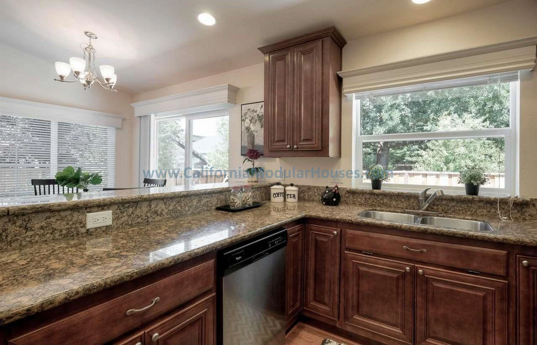 Modulars for Martinez, Contra Costa County, CA. Kitchen with granite countertops, wooden cabinets, a sink under a large window, and a view of the dining area. Prefab Accessory Dwelling Unit. California. Kitchen bar area.