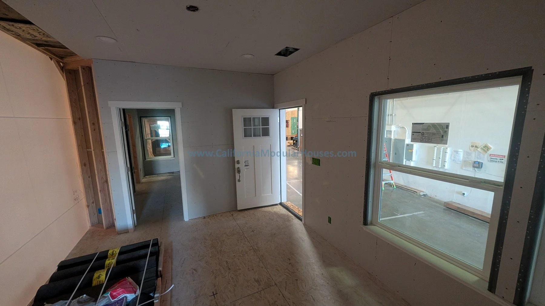 Sabastopol, CA.  Sonoma County, CA.  Pre-fab Modular Home.  ADU.  Interior of a house under construction with unfinished drywall, a window, a door, and construction materials inside.