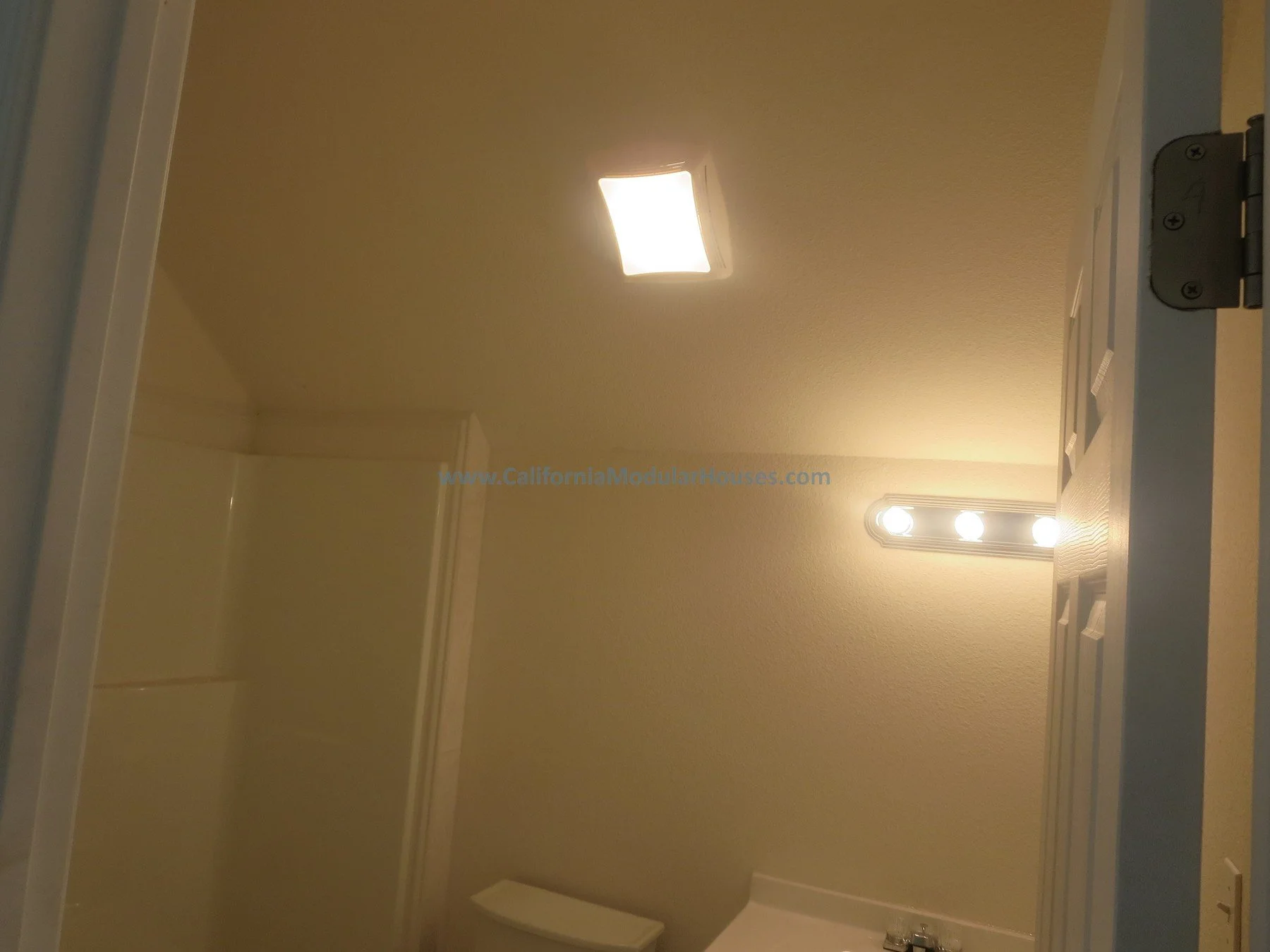 Bathroom ceiling with bright light and vanity mirror with three lights. California modular home.  New pre-fab modular house in Napa, California.   Unfinished attic.  