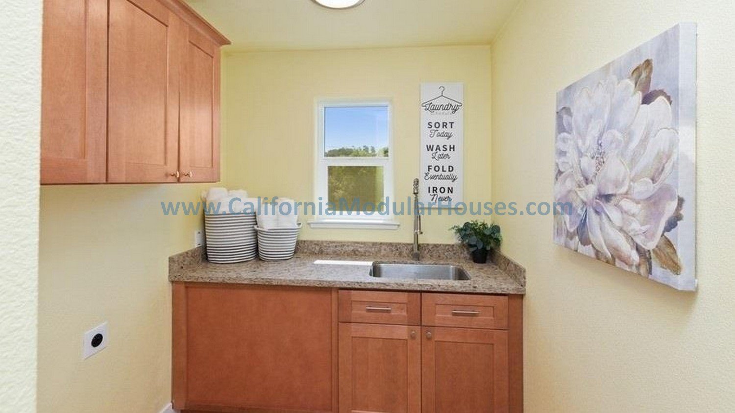 A small kitchen with light yellow walls, wooden cabinets, and a granite countertop.  California Modular Houses, Inc.  