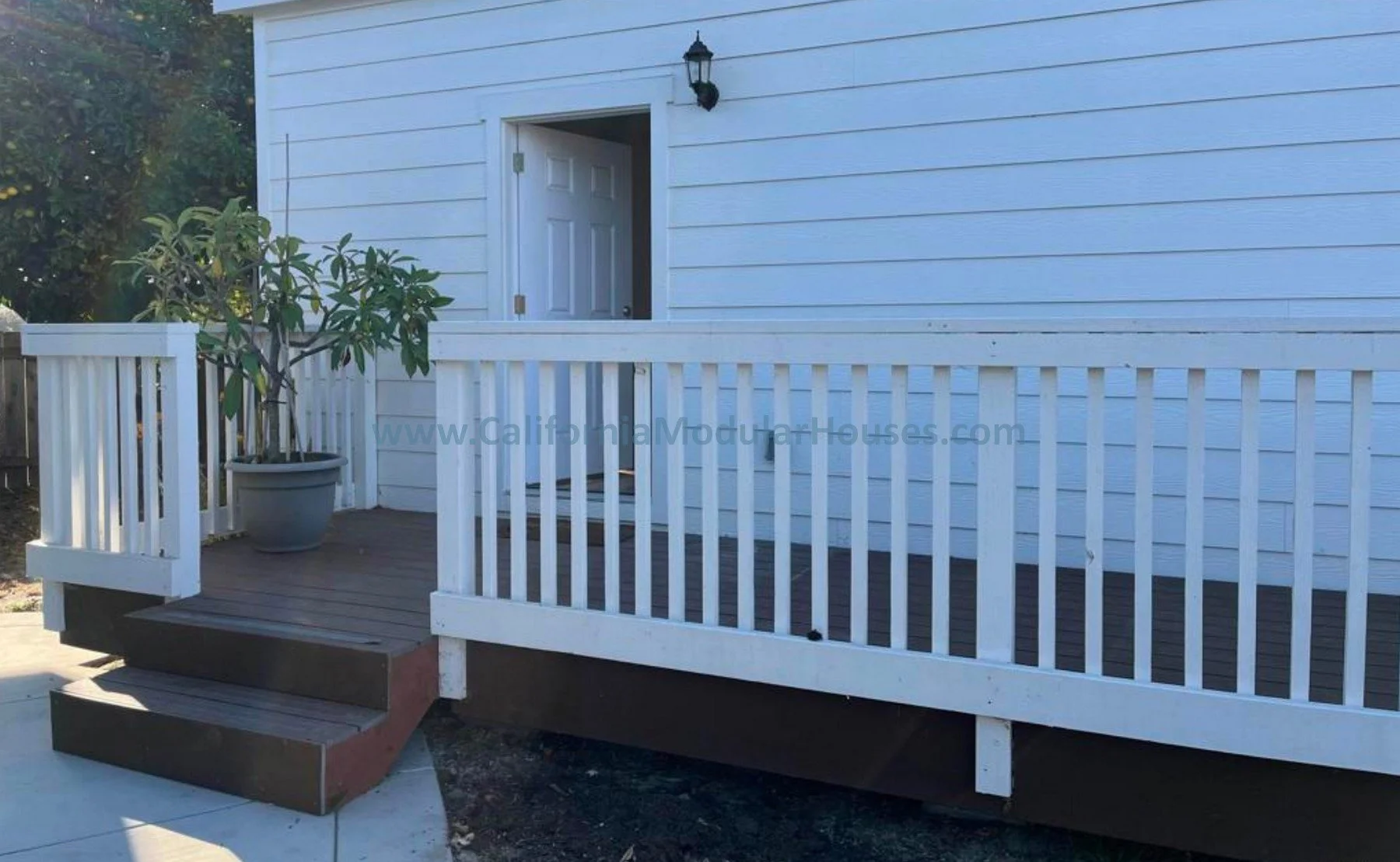 White wooden deck with steps leading up to a door on a white house.  San Diego County, CA. Prefab Modular ADU, Oceanside CA.  Accessory Dwelling Unit.  California Modulars. 