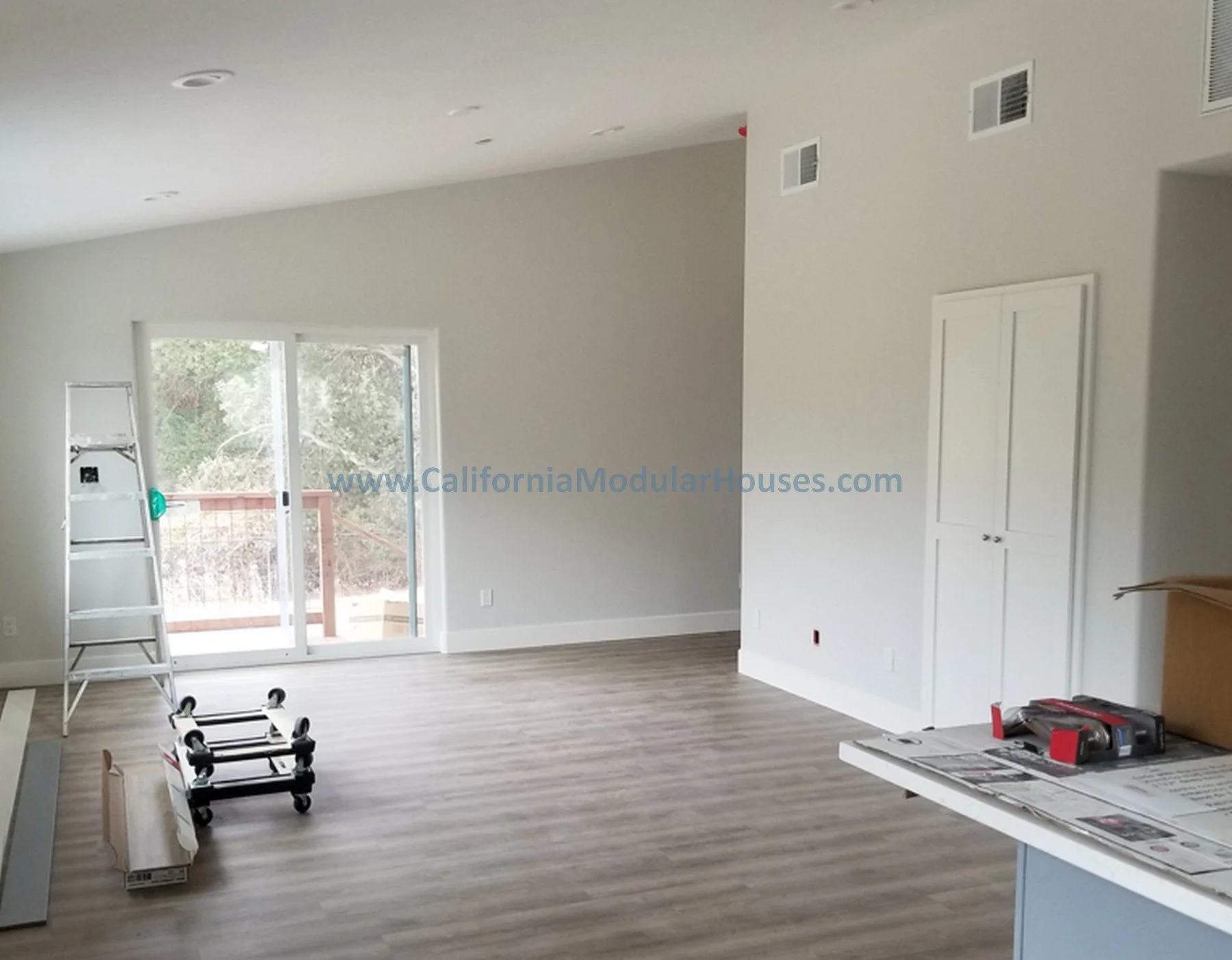 Empty living room with sliding glass door leading to a balcony, white walls, light wood flooring.  Interior picture of Accessory Dwelling Unit Contra Costa County, CA