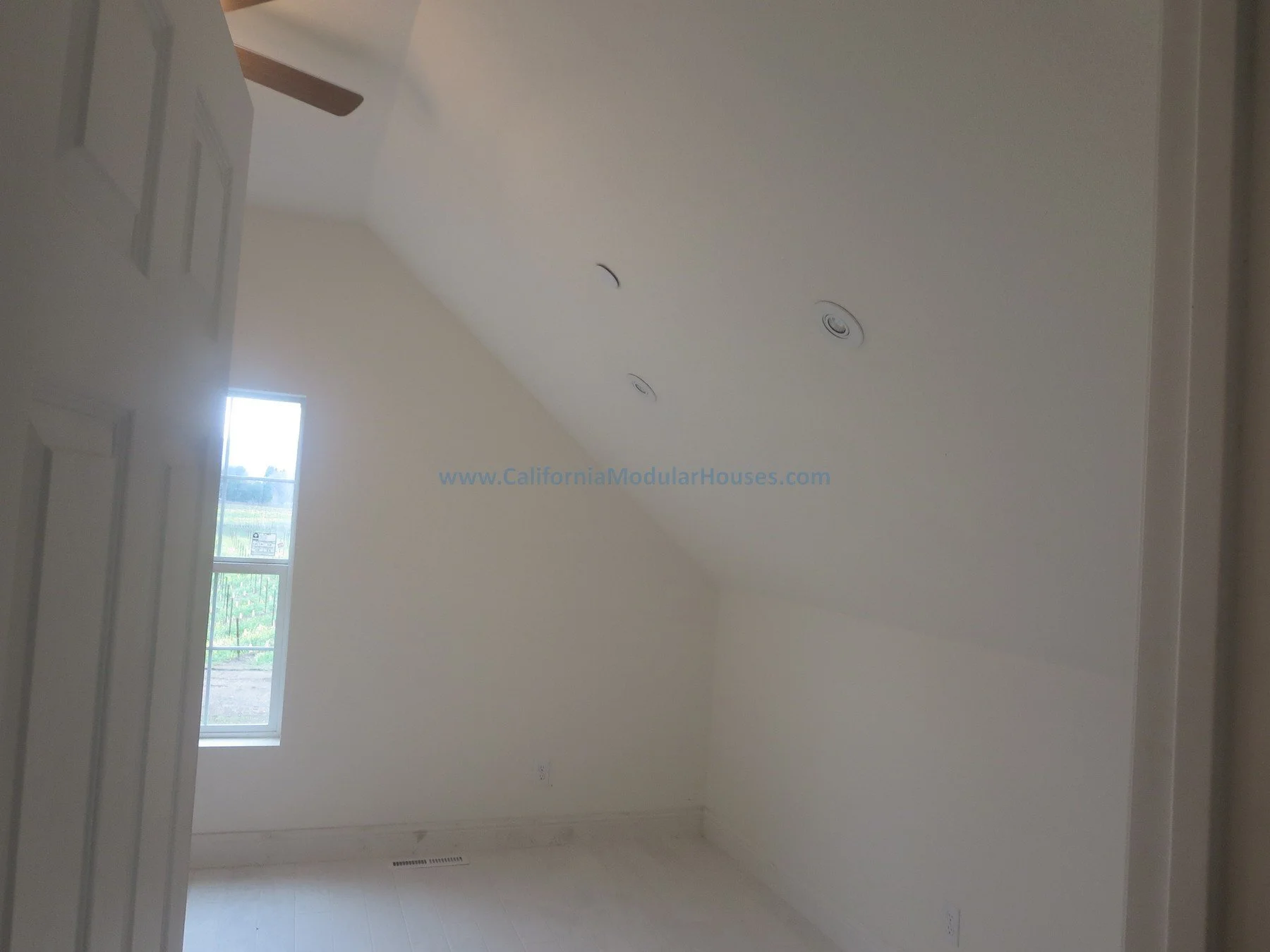 Empty room with a window, white walls, sloped ceiling with recessed lighting, and a ceiling fan, in a house under construction. Napa County, CA. Modular. Pre-fab Modular.  Cape Cod.  Modulars for Napa.  