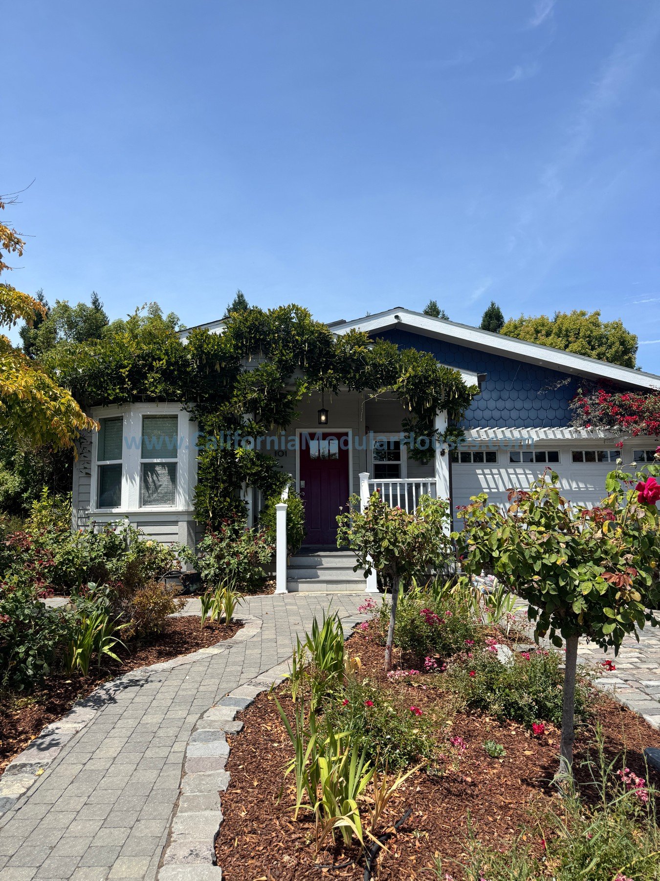 A charming house with a garden and a brick pathway leading to the front door.