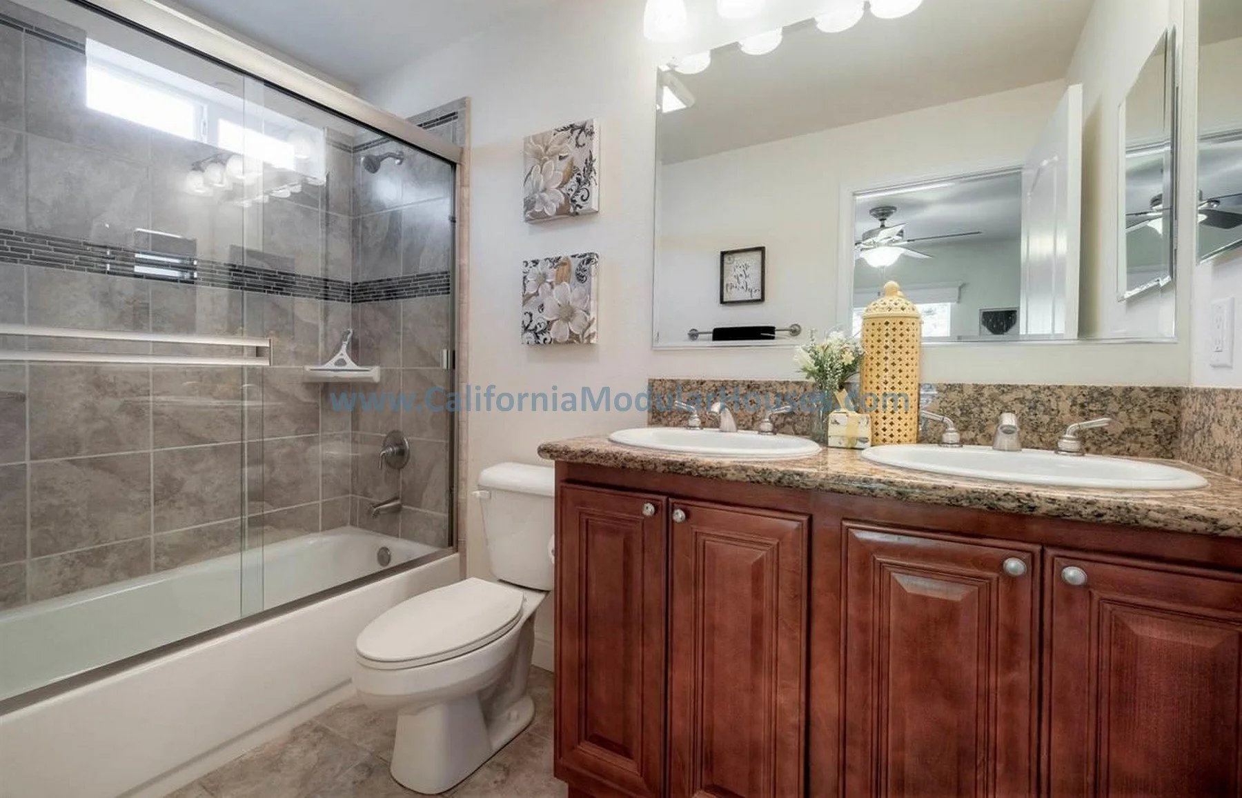 Bathroom with a glass-enclosed shower, toilet, and wooden vanity with two sinks and granite countertop.  The Teal Modular.  Prefab ADU California.  California prefab ADU.  Prefab Accessory Dwelling Unit. Modulars for Martinez, Contra Costa County, CA