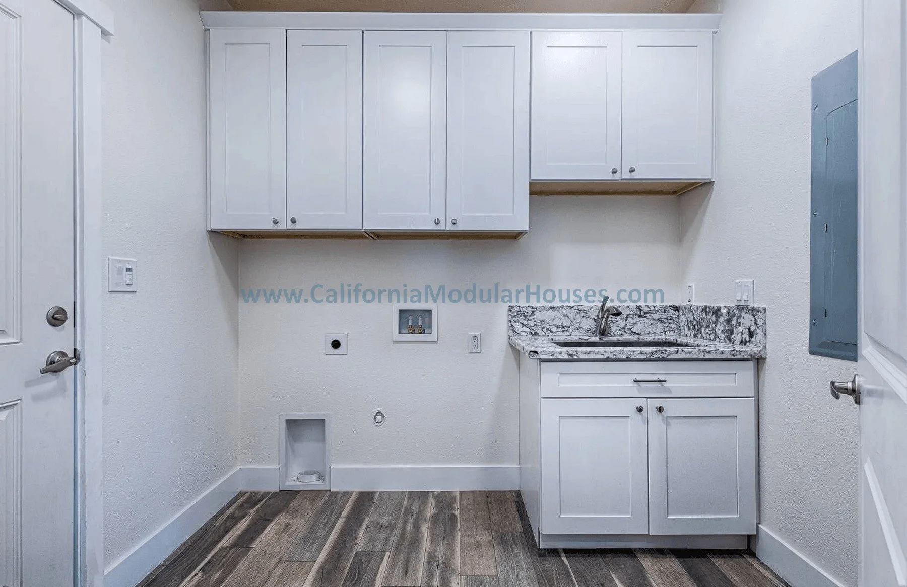 Empty laundry room with white cabinets, granite countertop, and wiring connections on the wall.
