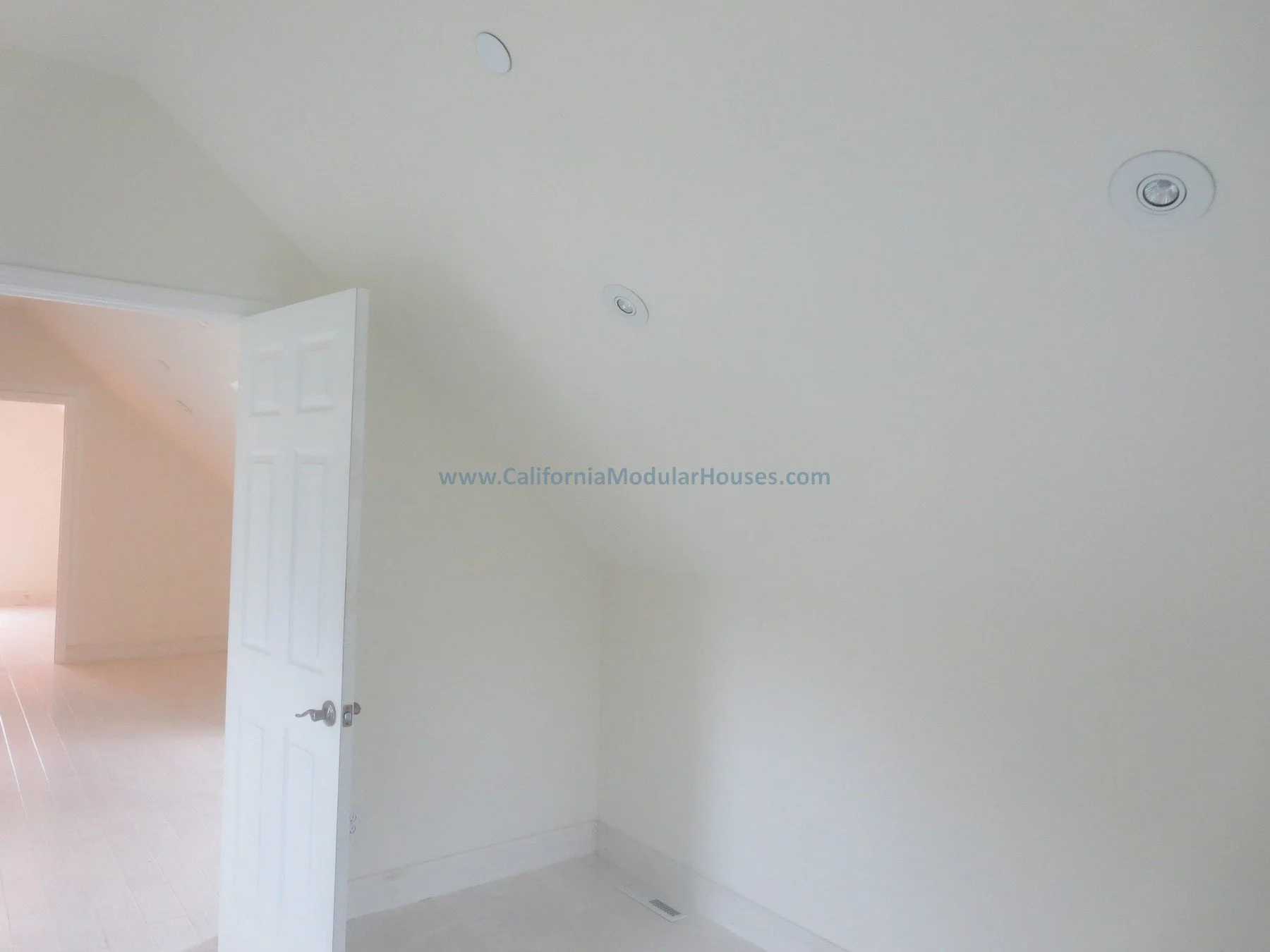 Pre-fab Modular.  Cape Cod.  Modulars for Napa.  Napa County, CA. Modular.  Empty room with white walls and ceiling, open door leading to another room with similar light-colored flooring, ceiling lights, and a floor vent.