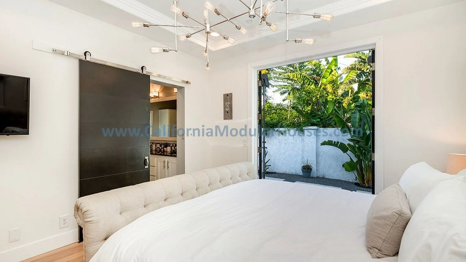 This is a well lit bedroom with site installed lighting to show off the coffered ceiling that also has moulding.  There is also a barn door to the bathroom to show what can be added after the modular home is delivered.  