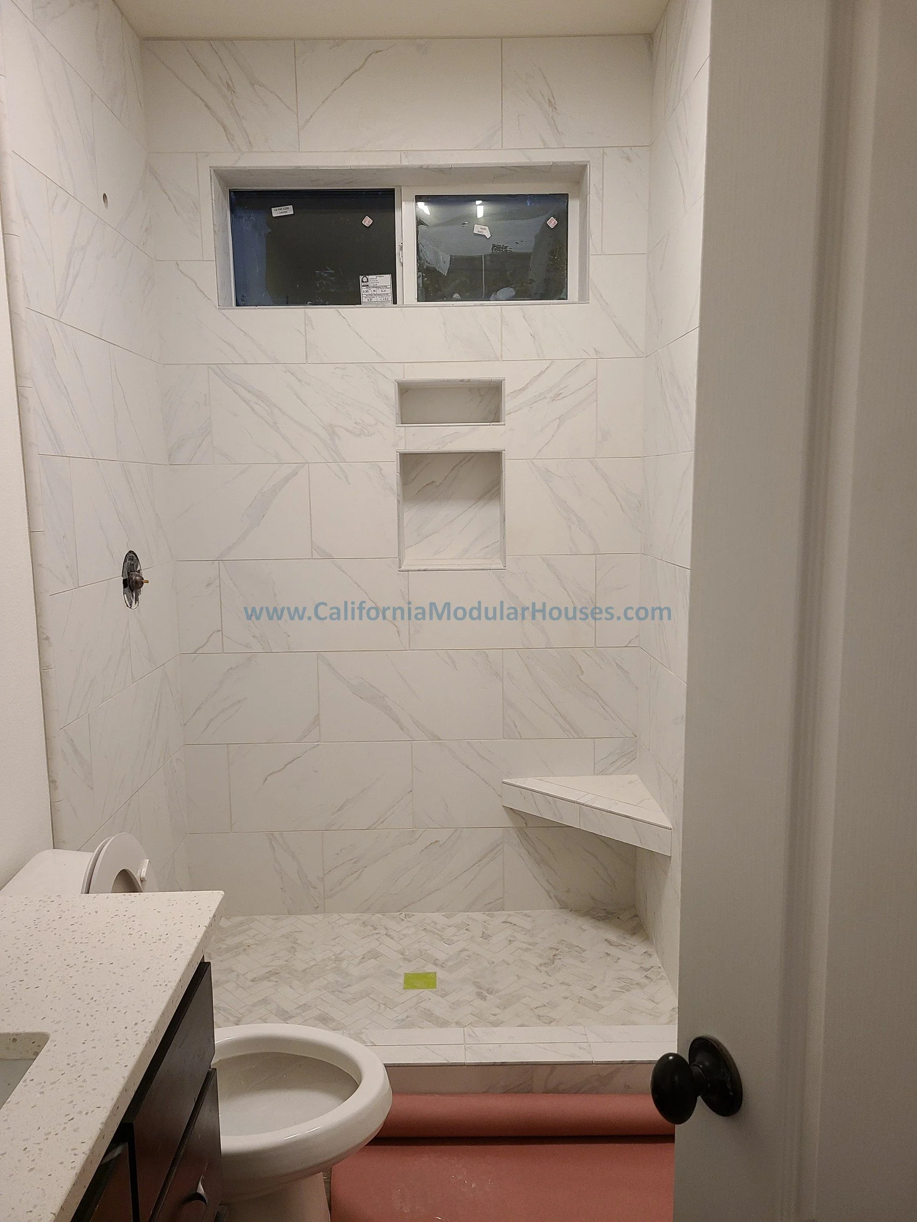 Bathroom with a marble shower, a small window, a built-in bench, an empty toilet, and a countertop with a sink.  City of Santa Barbara, Santa Barbara County, CA.   Modular Home CA,California Modular Homes.