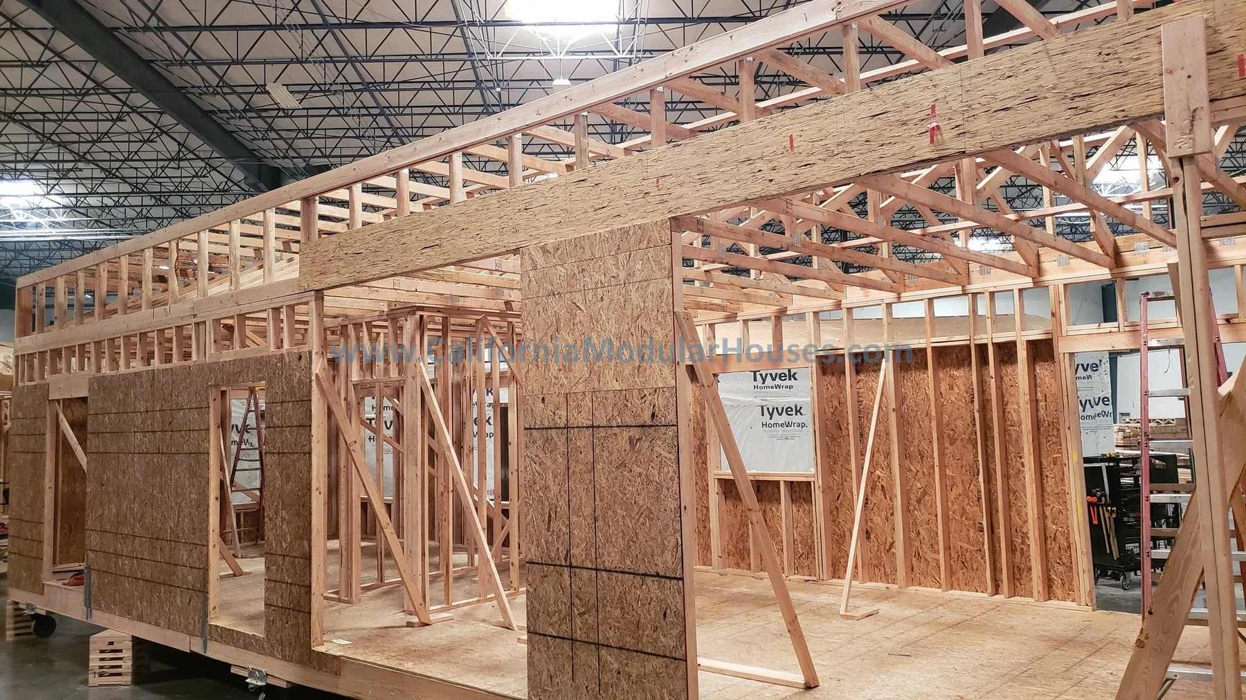 Wooden framing under construction, inside a building, with walls and roof partially built.