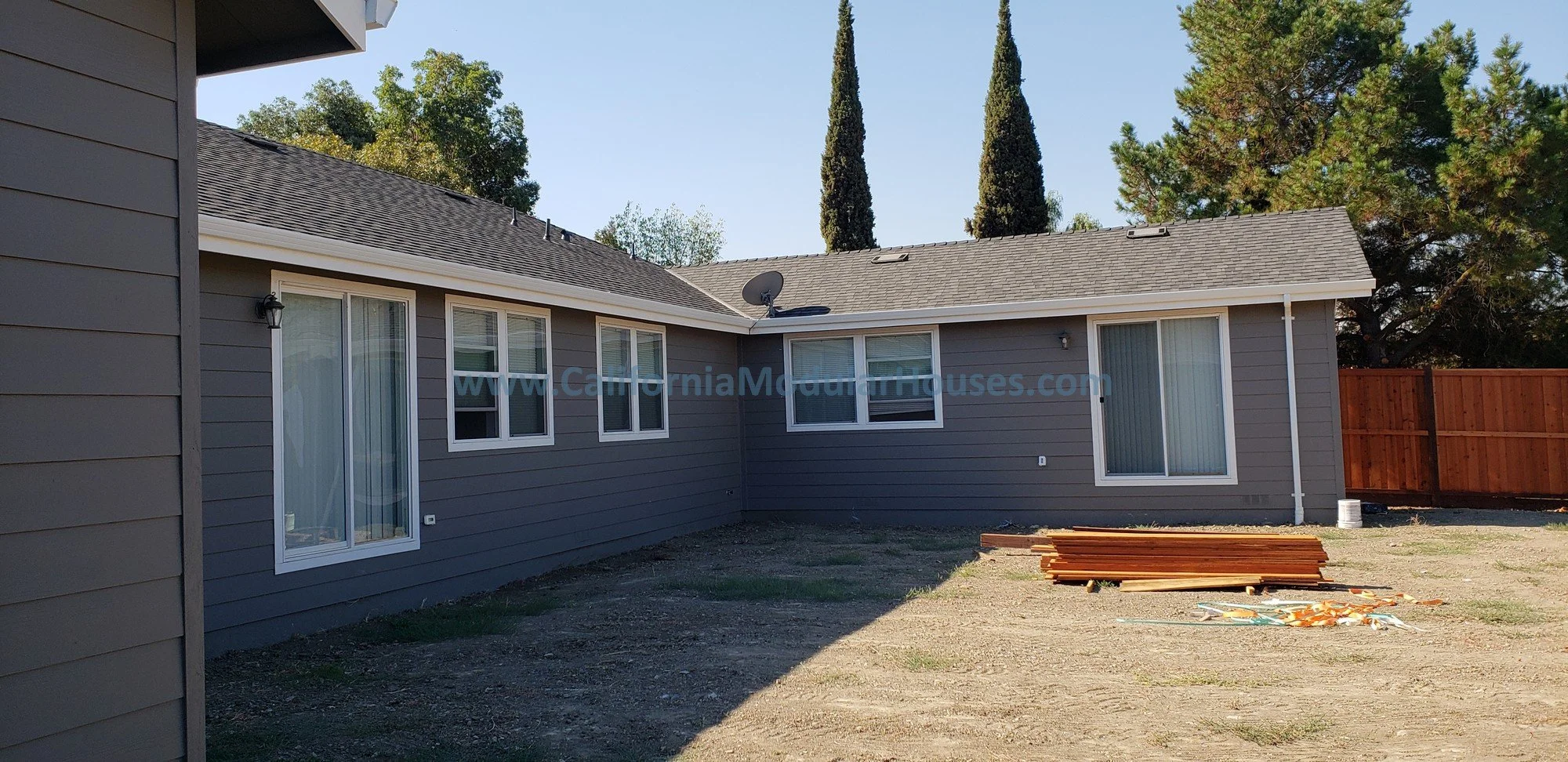 This home in Concord, CA shows the rear of the pre-fab house before the landscaping is done, showing two sliding glass doors and lots of windows.  