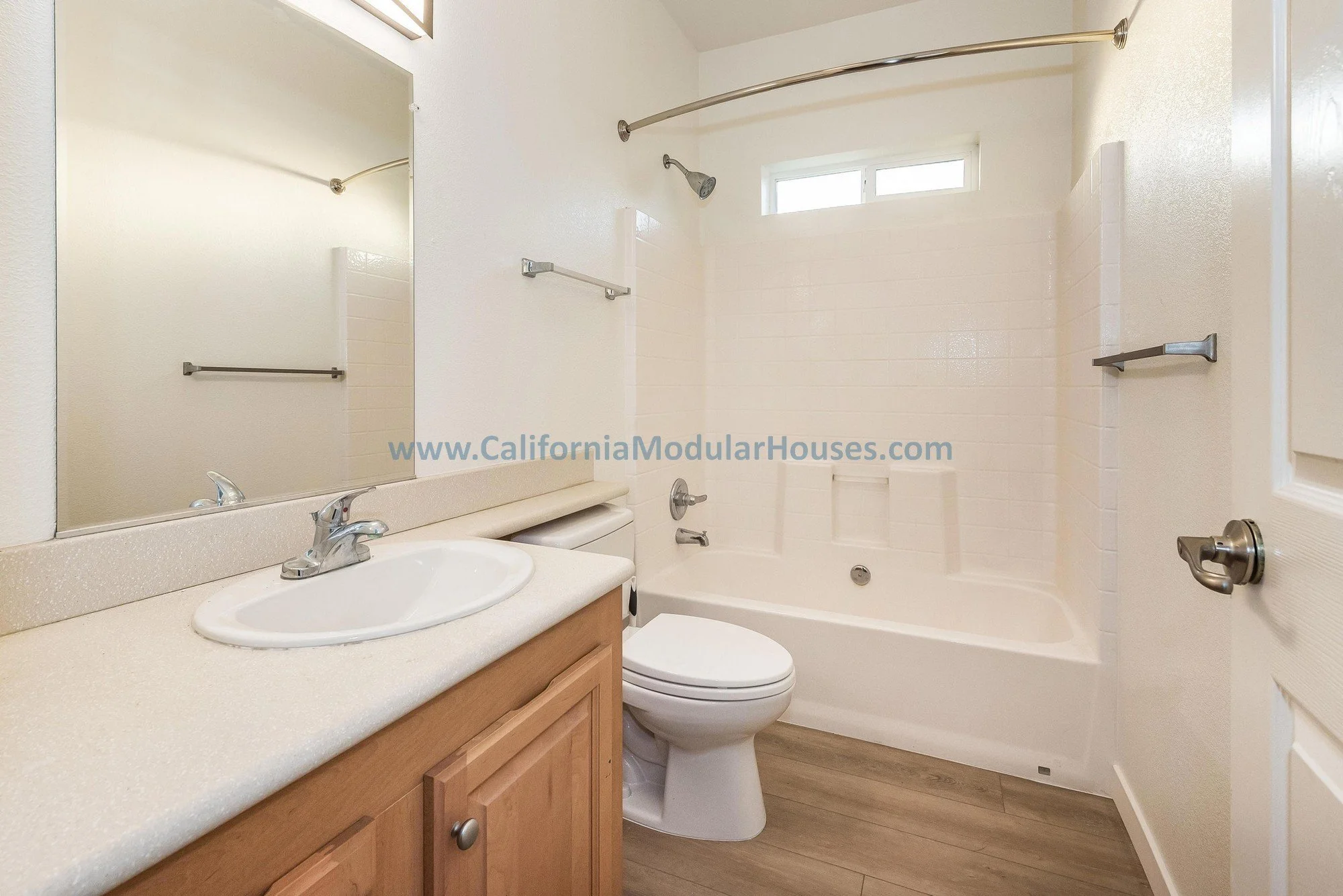 Cherry oak cabinets, white quartz countertop, porcelain sink of a guest bathroom of a prefab modular two-story home.