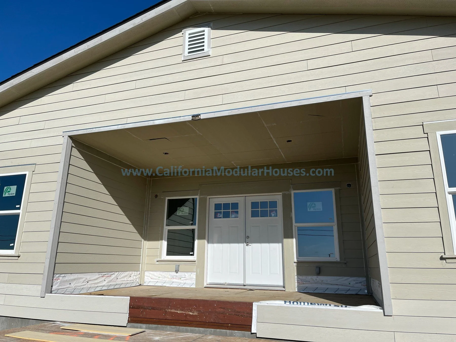 Front view of a beige modular house under construction with an open front porch area, window Image J exterior of a modular home that has 3 bedrooms and 2 bathrooms California modulars CA prefab
