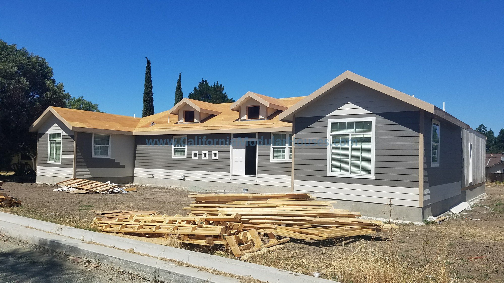 This shows the siding that was completed in the factory in gray, then the roof was completed on-site since the roof pitch prevented it from being delivered with the roof completed.  This view is from the front.  Modular Home.  