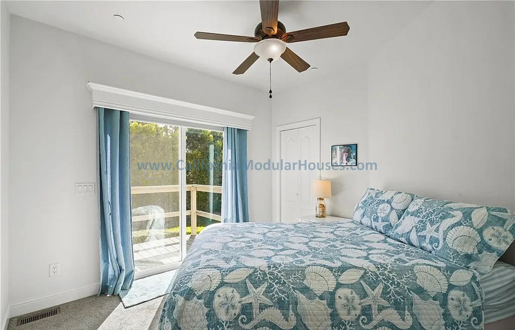 Bedroom with white walls, a sliding glass door leading to a porch, a ceiling fan.  California Modular Houses. Pre fabricated homes.  Modular houses for California.  Casas modulares.  Coastal California.  Ventura County, CA.  