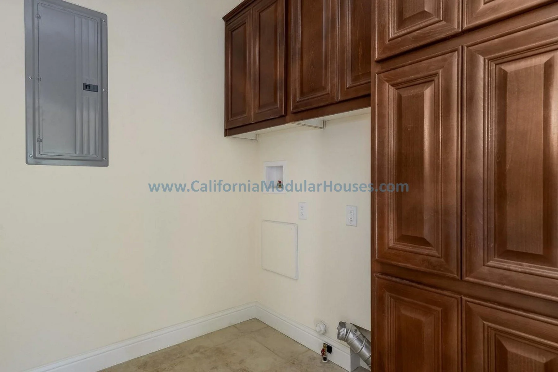 Empty laundry or utility room with beige walls, wooden cabinets, a gray electrical panel, and hookups and vent for washer and dryer.  San Jose, Santa Clara County, CA. Modular Home CA, California Modular Homes,