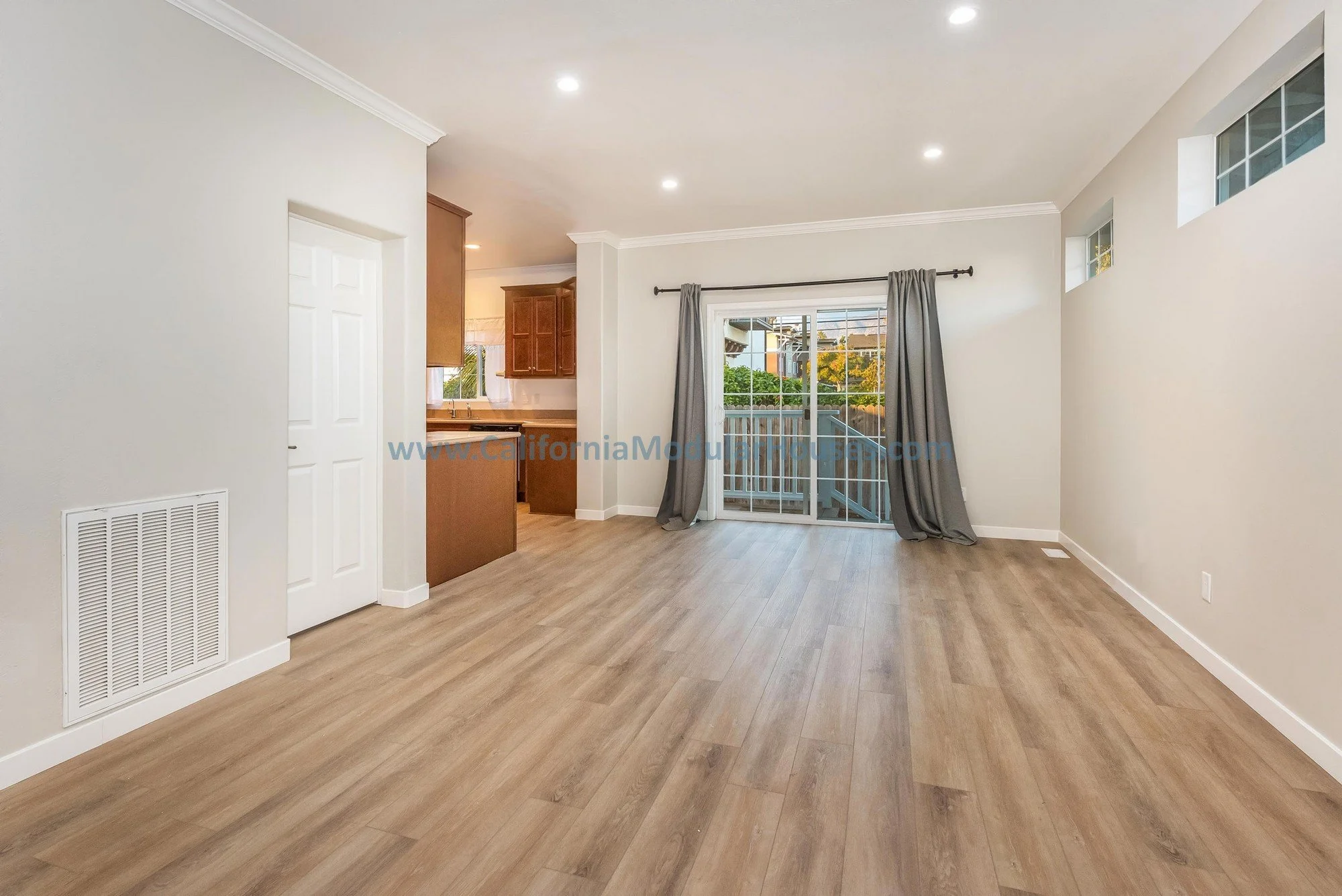 Living room of a prefab modular, brown wooden floors, gray drapes.