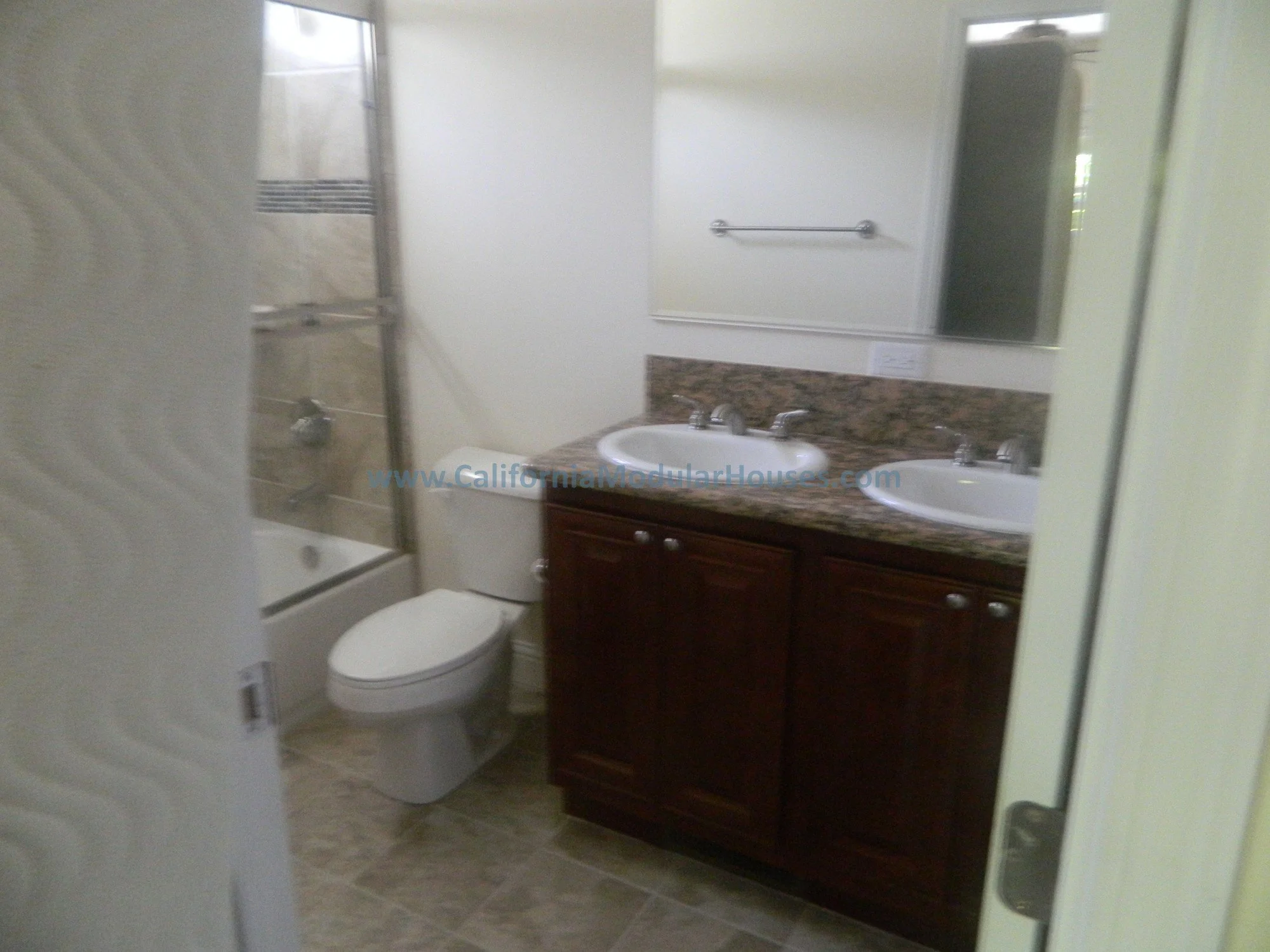 Bathroom with a bathtub and shower, toilet, and a double-sink vanity with a mirror above.