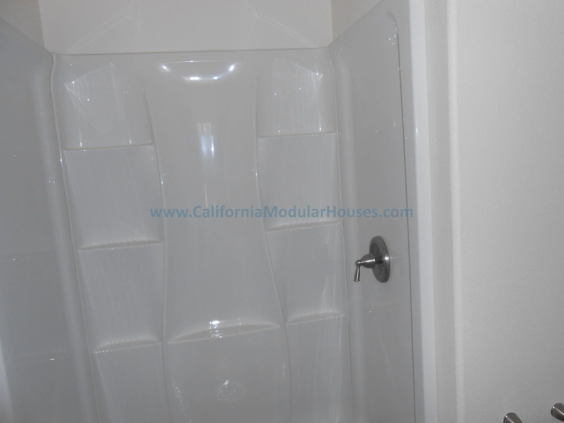 Empty white composite shower with a silver faucet on the right wall.   Modular Homes Northern California, Modular Homes in California, California Modular Home, Two-Story Modular Home.  