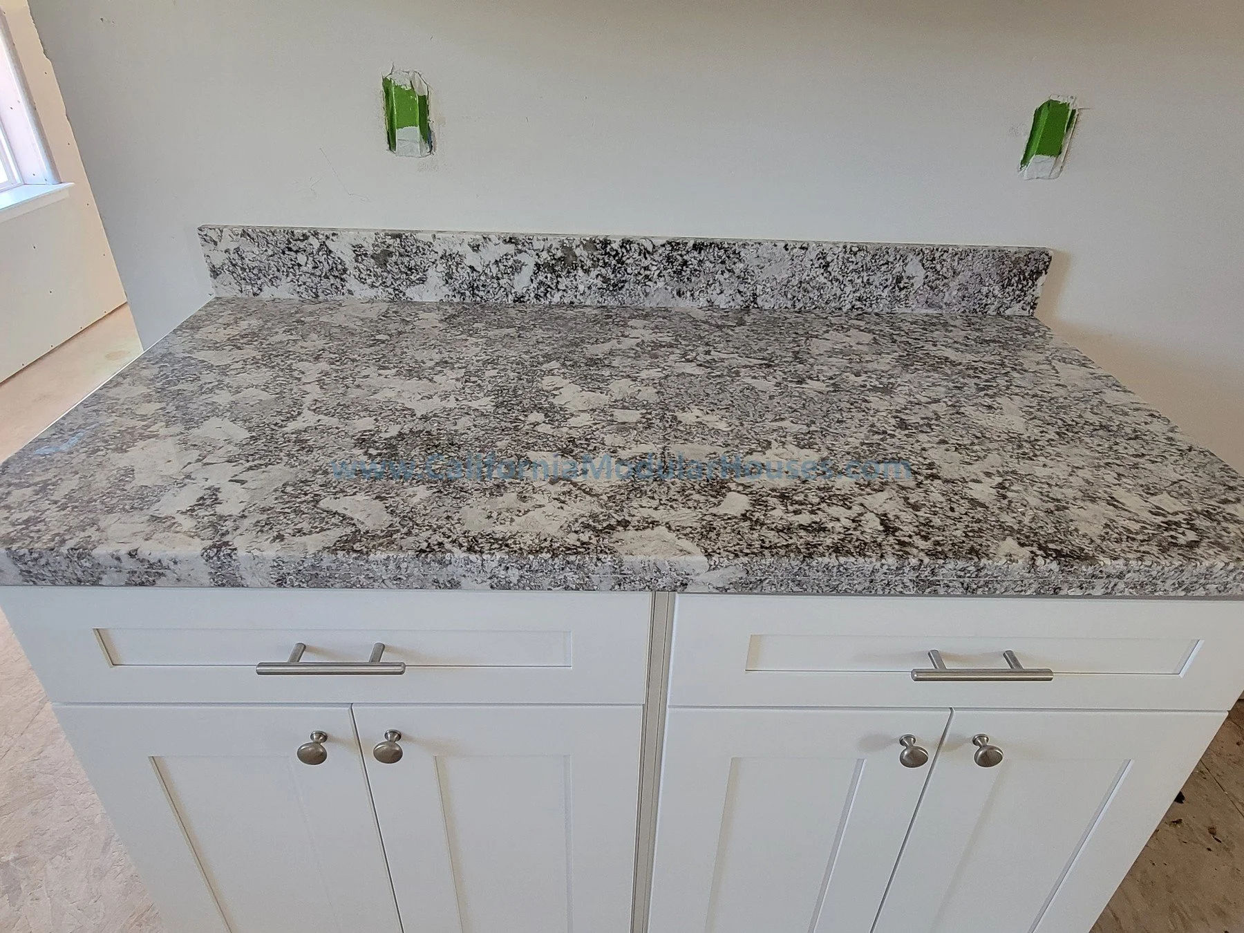 Kitchen countertop with gray, black, and white speckled granite surface.