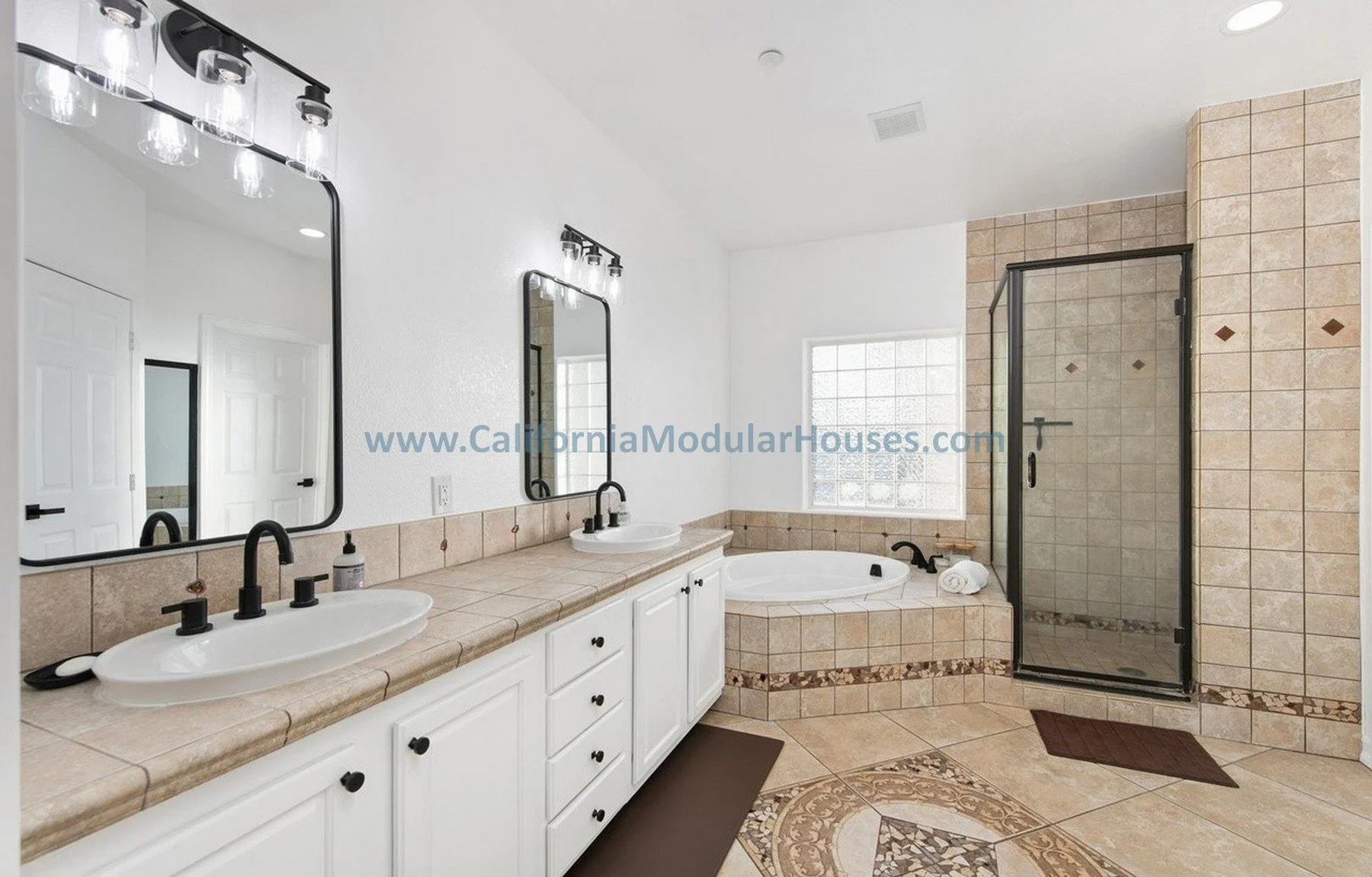 Bathroom with double vanity sinks, large mirrors, a bathtub, and a tiled shower enclosure. White cabinets under a beige tiled countertop, and a window providing natural light.